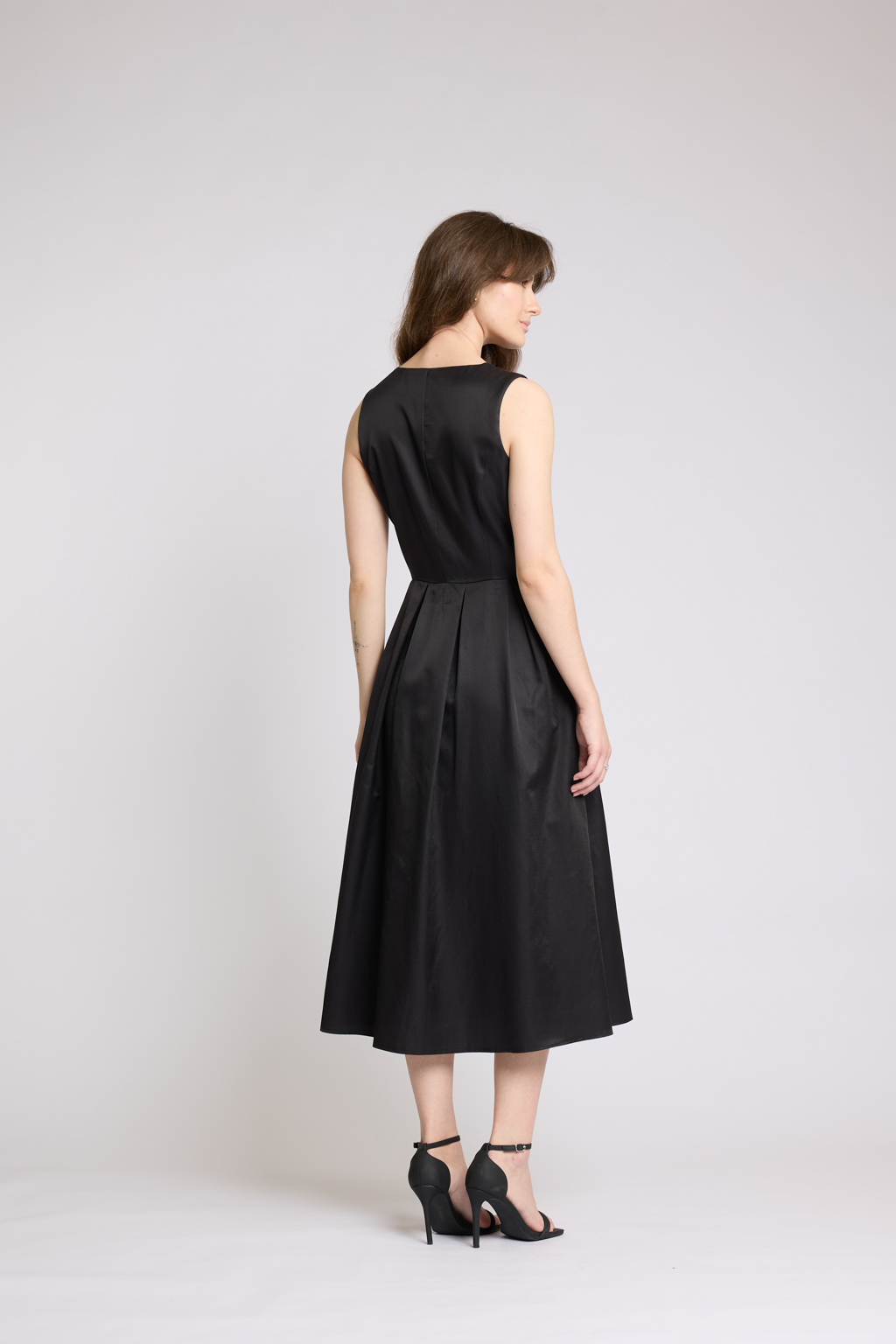 Платье длины миди с V-образным вырезом с декоративными пуговицами. Юбка пышная со складками. По бокам карманы.