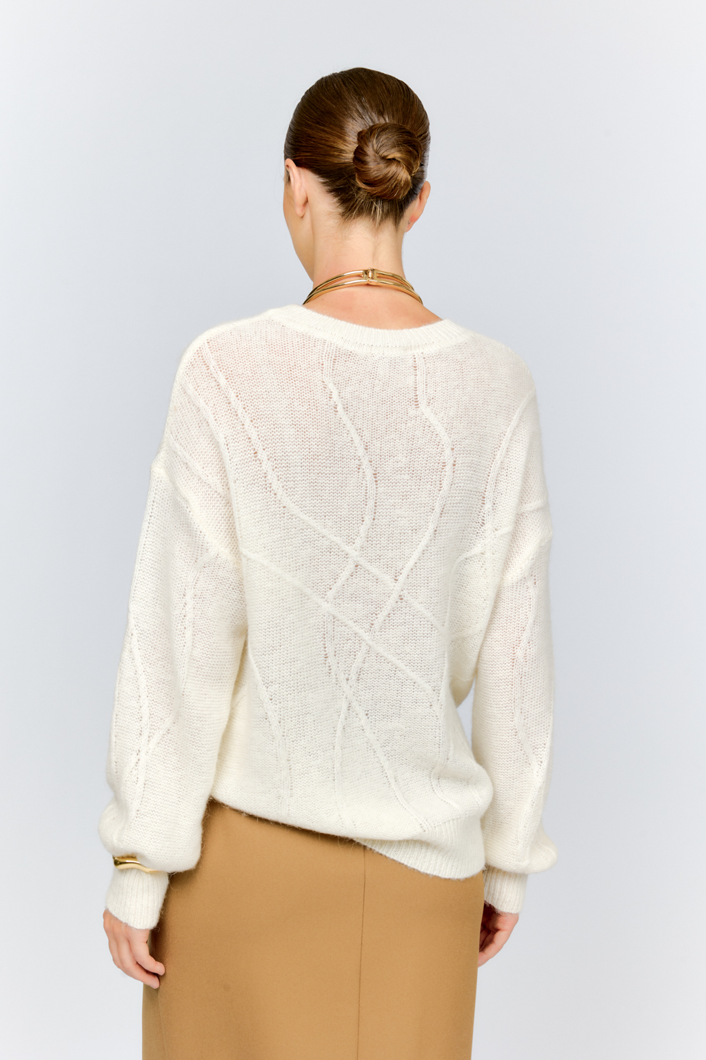 Нежный молочный  джемпер из мягкой шерстяной пряжи с трендовым ажурным дизайном, круглой горловиной, со спущенной линией плеча и длинными рукавами имеет  свободный силуэт оверсайз. Уникальный узор привлекает внимание и придает образу стильный акцент.