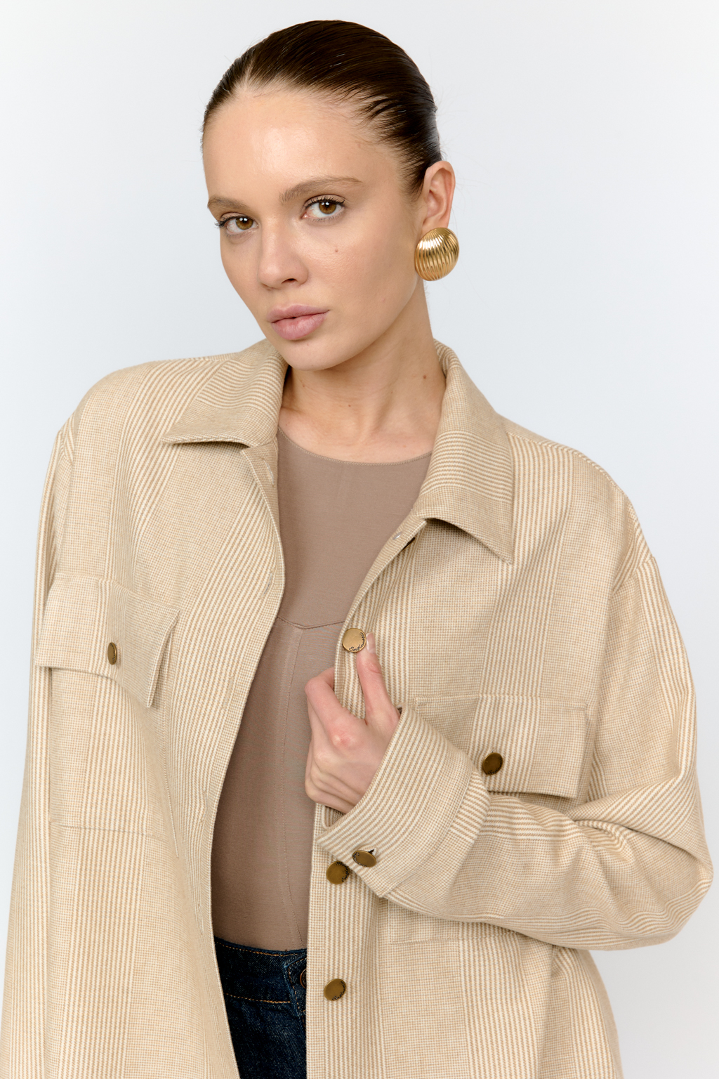 Рубашка свободного кроя с накладными карманами и застежкой на металлические пуговицы-болты из клетчатой костюмной ткани с peach-эффектом идеальна как для многослойных образов с футболками и водолазками, так и в качестве самостоятельной единицы.