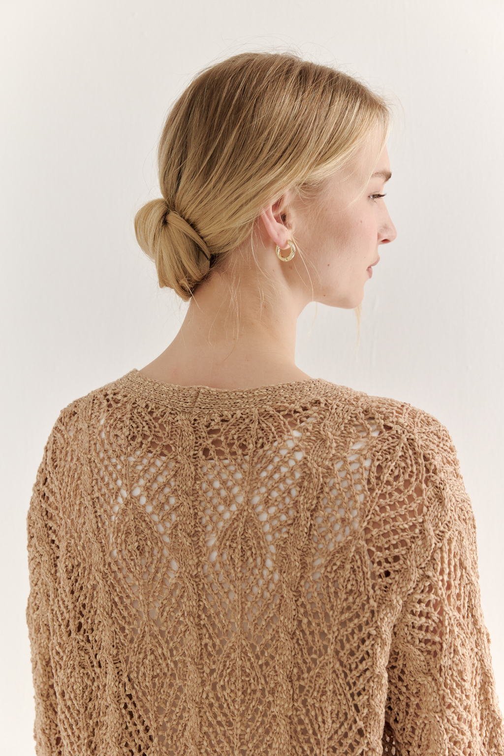 Бежевый вязаный кардиган оверсайз силуэта из хлопковой пряжи. Кардиган связан в сложной технике комбинирования сетки и ажурных ромбов. Рукав прямой удлиненный, V-образный вырез, борт отделан планкой, застежка по борту на 3 пуговицы, низ кардигана и рукав – сложные фестоны.