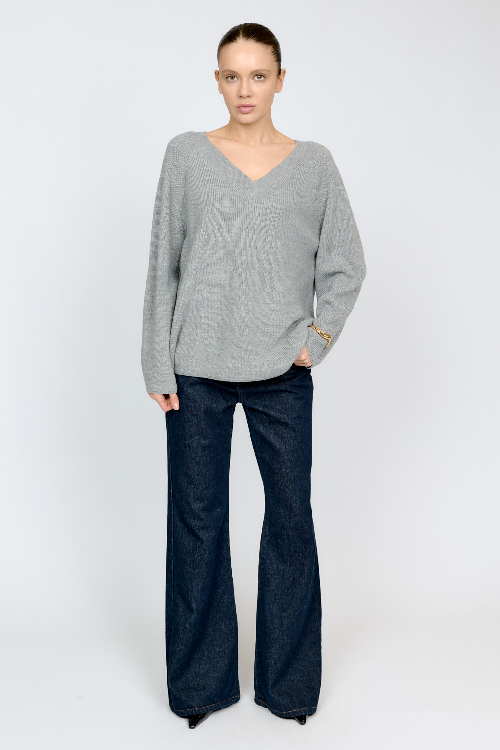 Трикотажный джемпер серого цвета свободного силуэта с V-образным вырезом горловины и рукавами реглан из шерстяной смесовой пряжи станет центром комфортных осенних образов.