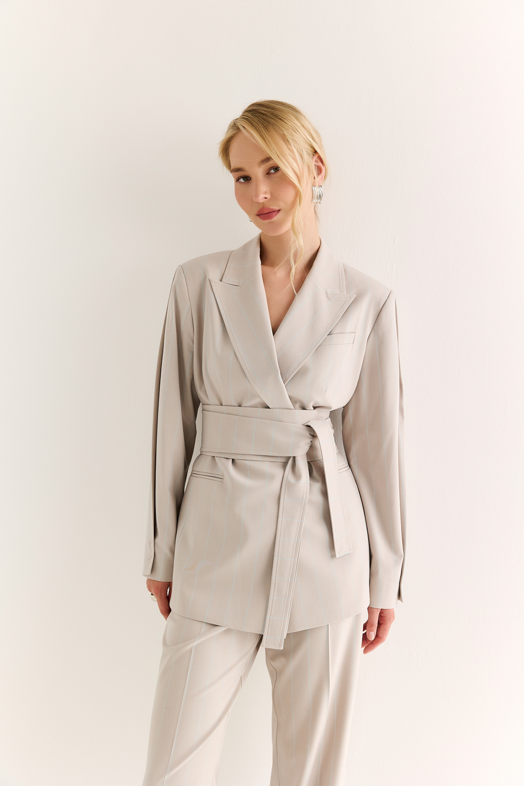 Жакет с поясом-кушаком: мягкая сила и подчёркнутая линия. Этот жакет сочетает в себе структурированную форму и пластичность драпировки. Приталенный силуэт акцентирован широким поясом-кушаком, который завязывается на талии, формируя выразительную линию «песочных часов» и добавляя образу женственности без излишней строгости.
Острые лацканы, аккуратная линия плеч и выверенный крой рукавов делают модель универсальной: для делового дня, кэжуал-комплекта или вечернего выхода. Пояс, завязанный на узел или бант, задаёт настроение и подчеркивает индивидуальность. Гармония формы и мягкости. Жакет, который раскрывает силу через утончённость.