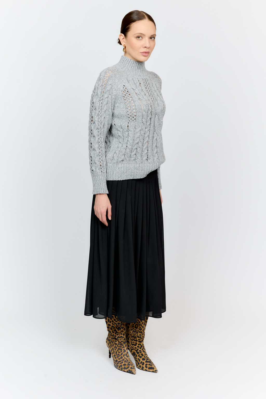 Свитер серого цвета из мягкой пряжи фигурной вязки с ассиметричными косами, с высокой горловиной и длинным рукавом реглан отлично стилизуется с денимом и обувью на плоском ходу.