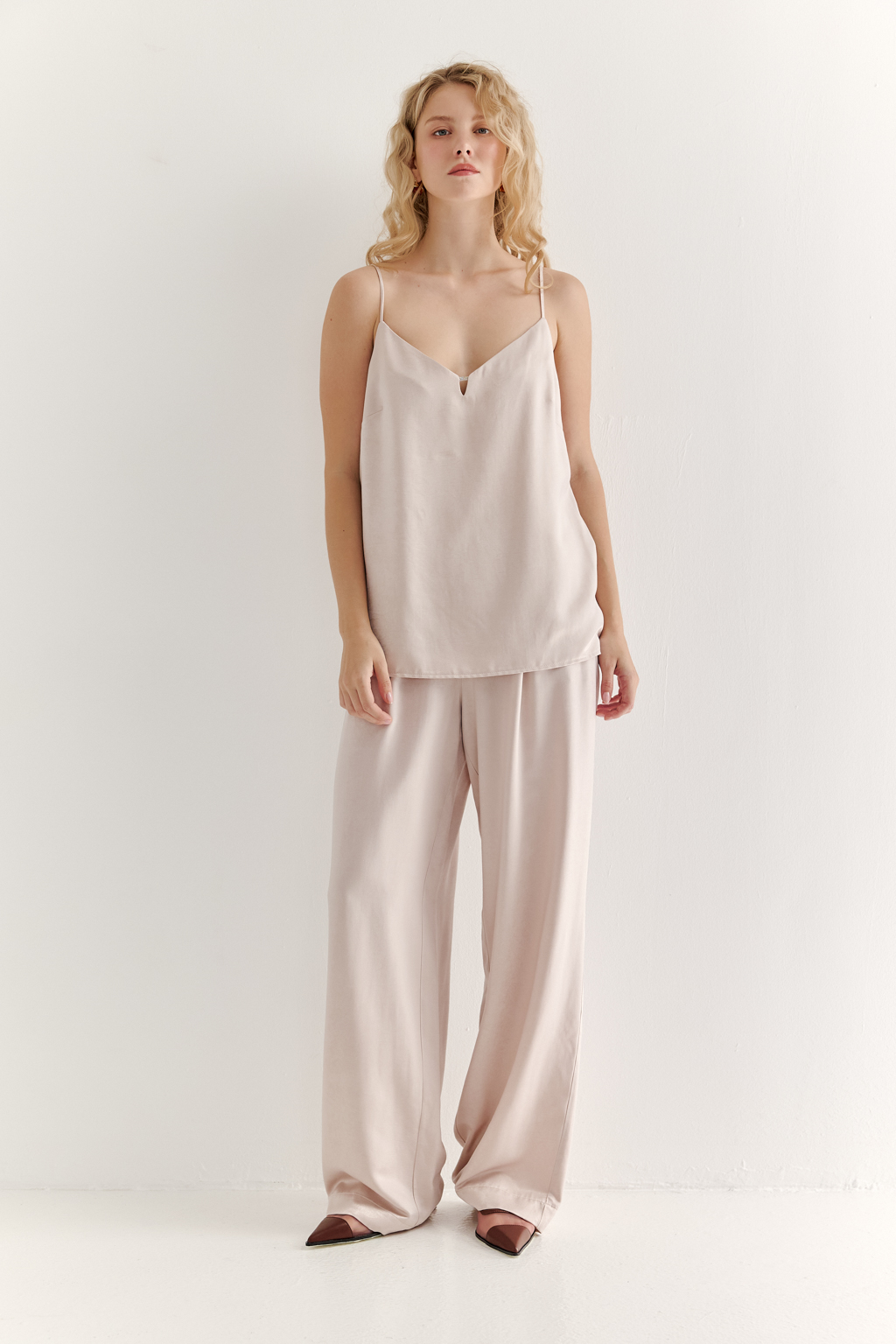 Топ из струящегося атласа с крэш эффектом в пудровом цвете. Топ на регулируемых бретелях свободного кроя с декором на линии декольте.