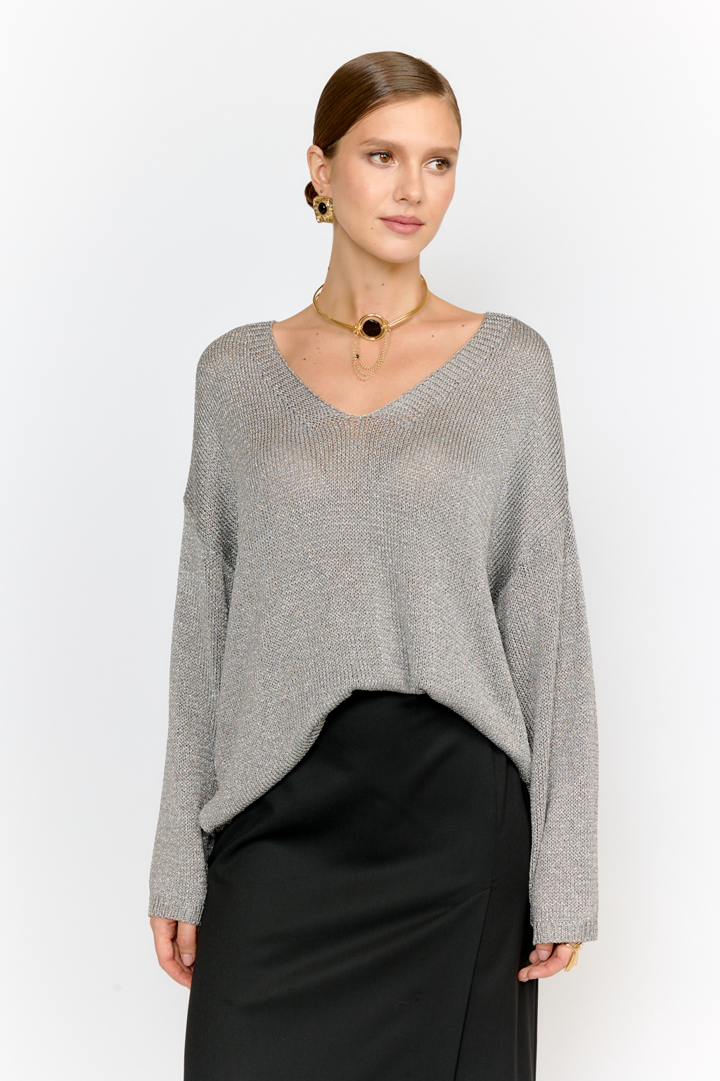 Модель джемпера с V-образным  вырезом горловины и свободным кроем выполнена из премиальной пряжи с вискозой в составе. Металлизированное волокно придает пряже  мерцание. Мягкие ниспадающие линии джемпера красиво драпируют фигуру. Базовая по крою модель, выглядит уникальной  благодаря эффектному металлизированному блеску и серо-серебряному цвету пряжи. Элегантный силуэт с длиной выше бедер и изящным V-образным вырезом подчеркивает женственность и создает безупречный образ.