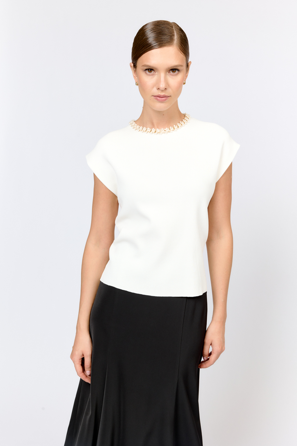 Элегантный топ  с круглой горловиной, декорированной тесьмой. Со спущенным плечом, без рукавов. Свободного силуэта. Изысканная модель из премиального  трикотажа плотной вязки в  молочном цвете. Сбалансированная комбинация вискозы и полиамида  создает комфорт при носке. Материал хорошо держит форму  и не подвержен деформации.  Лаконичный топ с декоративной тесьмой  в молочном оттенке - утонченное решение для вечерних или деловых образов.