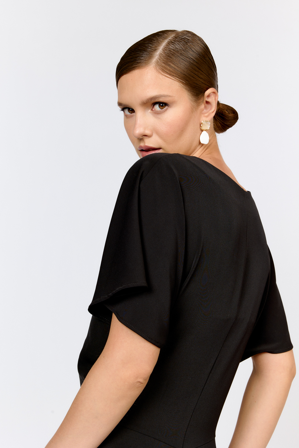 Струящееся платье свободного кроя с цельнокроеными рукавами и открытой горловиной с V-образным вырезом горловины. Модель с декоративной пряжкой на притачном поясе со сборкой по бокам. Выполнено из эластичной плательной ткани. Полиэстер придает ткани устойчивость к сминанию и хорошо держит форму. Что позволяет изделию сохранять опрятный вид в течении дня.  Глубокий черный цвет не тускнеет после стирки. Спандекс добавляет эластичность, обеспечивая идеальную посадку по фигуре. Преимущества ткани: новое современное качество с мягким блеском и благородной фактурой. Ткань легкая, приятна к телу, красиво драпируется при движении. Глубокий черный оттенок придает изделию благородный вид.