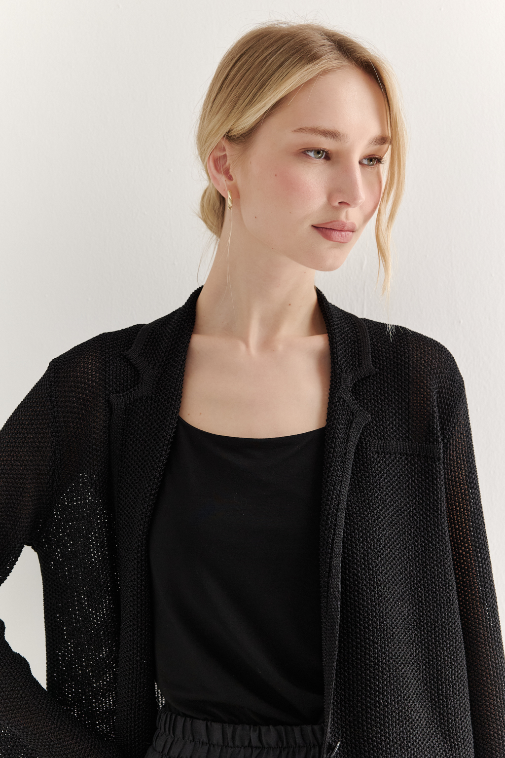 Жакет полуприлегающего силуэта черного цвета из вязаного трикотажа, в составе которого вискоза и хлопок. Плотная скрутка нити образует упругое, но в то же время дышащее полотно. Цельно вязаные лацканы элегантно переходят в воротник, обрамляя вырез. Прямые рукава полной длины завершают лаконичный силуэт. Этот жакет станет изысканным дополнением к непринужденному городскому образу.