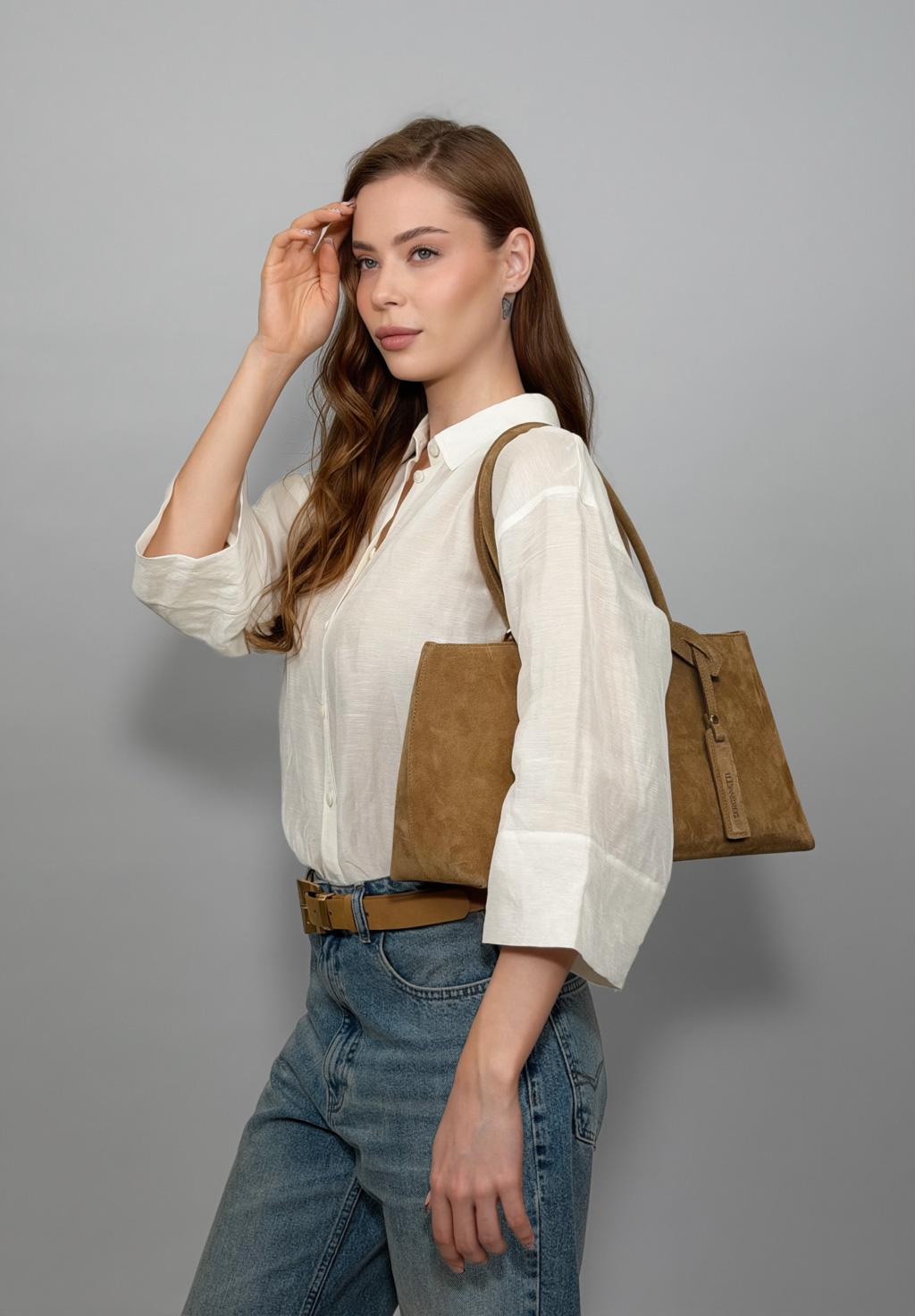 Сумка-тоут выполнена из натуральной замши. Аксессуар закрывается на металлическую молнию,имеет удобные ручки и брелок. Размеры сумки: 45*21*5,8 см.