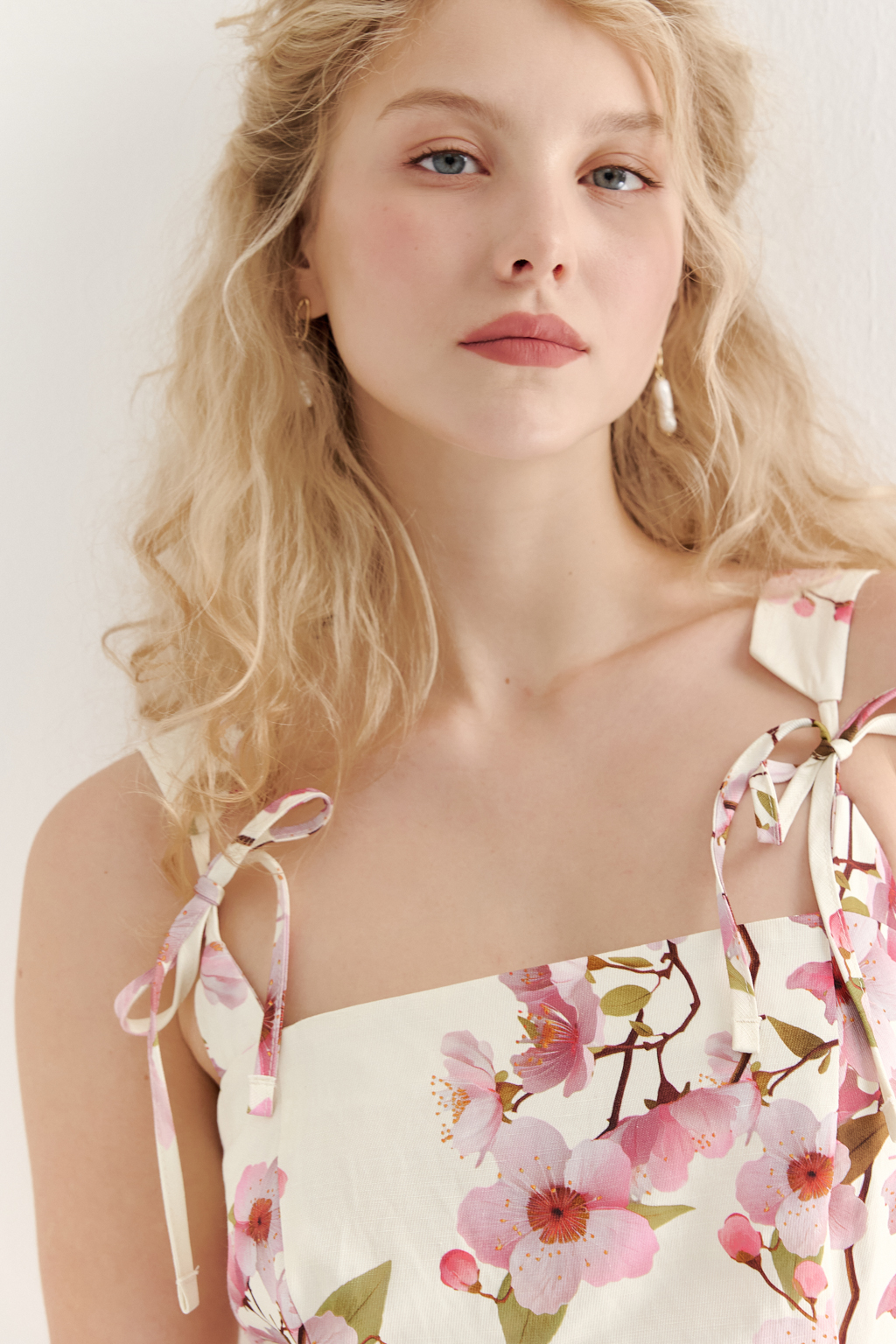 Платье-сарафан полуприлегающего силуэта выполнено из плотной пластичной ткани в основе которой волокна вискозы и льна. Лиф-бандо, акцент на линию талии и юбка полусолнце формируют изящный Х-образный силуэт. Особую утонченность платью придают бретели сложной формы, изящно завязывающиеся на шнуры. Эластичная деталь на спинке платья, собранная на нити-стрейч, и застежка-молния в боковом шве обеспечивают комфортную и превосходную посадку по фигуре. Ключевой деталью, выделяющей этот наряд, является эксклюзивный принт, разработанный в дизайн-бюро бренда. В этом принте нежные розовые цветы сакуры и молочный оттенок фона образуют гармоничное, элегантное сочетание, рождающее ощущение красоты и утонченности.