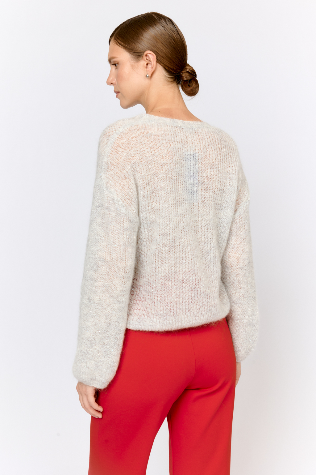 Кардиган с центральной застежкой на пуговицы, V-образной горловиной и длинным рукавом.  Модель свободного силуэта в жемчужно-сером  оттенке из воздушной пряжи с шерстью и мохером с деликатными мелкими пайетками, придающими легкое сияние. Кардиган очень теплый, несмотря но свою трендовую транспарентность и легкость, благодаря мохеру в составе. Шерсть так же обеспечивает естественную терморегуляцию и уют. Такой кардиган будет выигрышно смотреться в образах с  брюками и юбками из коллекции, а так же дополнит образы с платьями на бретелях или платьем-бандо.