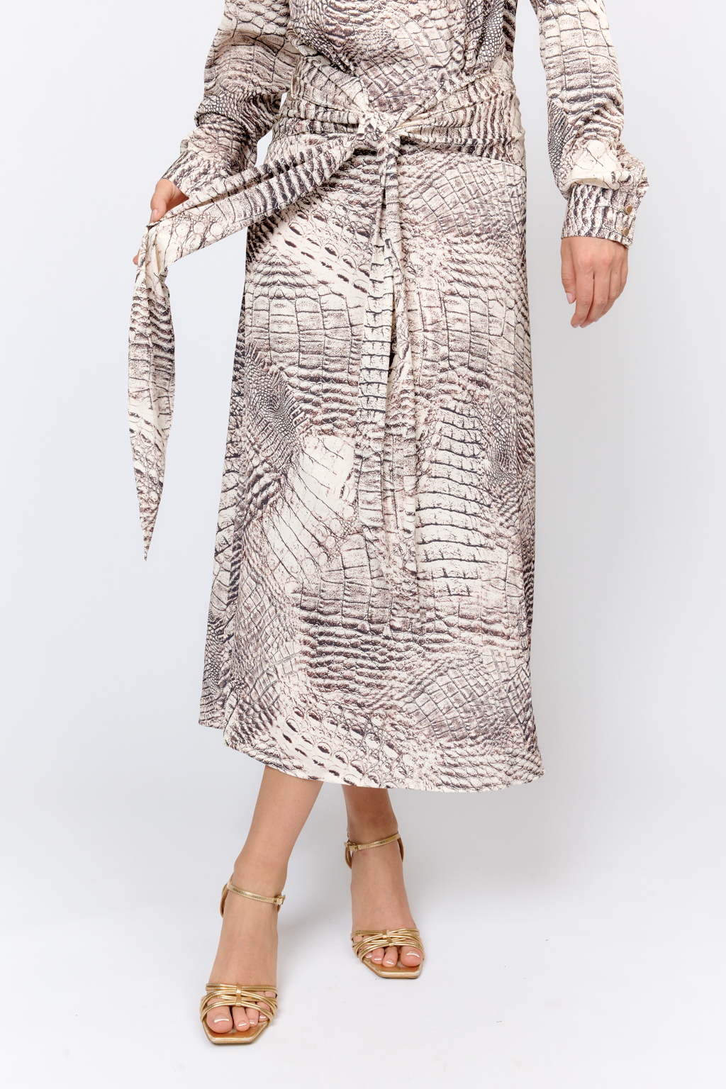 Струящееся женственное платье из легкой ткани с атласной фактурой и авторским принтом коллекции. Глубокий вырез горловины, сборка и завязки спереди делают модель эффектной, расклешенность по низу добавляет женственность, а принт уникальность. Преимущества ткани - полиэстеровая ткань с приятным жемчужным  блеском мягко драпируется, подчеркивая достоинства фигуры. Деликатный блеск придает изделию праздничный вид. При этом изделие  не требует сложности в уходе. Ткань легкая и прочная, устойчивая к механическим повреждениям.