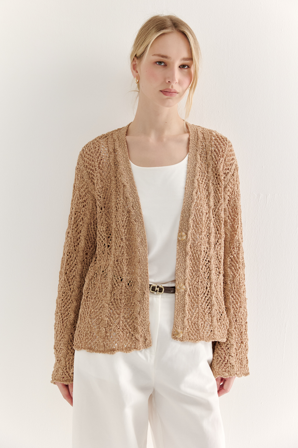 Бежевый вязаный кардиган оверсайз силуэта из хлопковой пряжи. Кардиган связан в сложной технике комбинирования сетки и ажурных ромбов. Рукав прямой удлиненный, V-образный вырез, борт отделан планкой, застежка по борту на 3 пуговицы, низ кардигана и рукав – сложные фестоны.