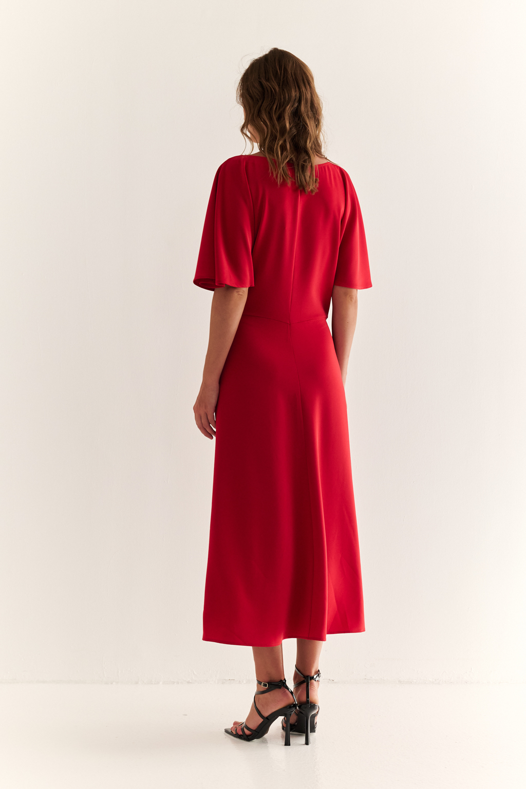Струящееся платье свободного кроя с цельнокроеными рукавами и открытой горловиной с V-образным вырезом горловины. Модель с декоративной пряжкой на притачном поясе со сборкой по бокам. Выполнено из эластичной плательной ткани. Полиэстер придает ткани устойчивость к сминанию и хорошо держит форму. Что позволяет изделию сохранять опрятный вид в течении дня.  Спандекс добавляет эластичность, обеспечивая идеальную посадку по фигуре. Преимущества ткани: новое современное качество с мягким блеском и благородной фактурой. Ткань легкая, приятна к телу, красиво драпируется при движении. Насыщенный красный цвет делает платье эффектным.