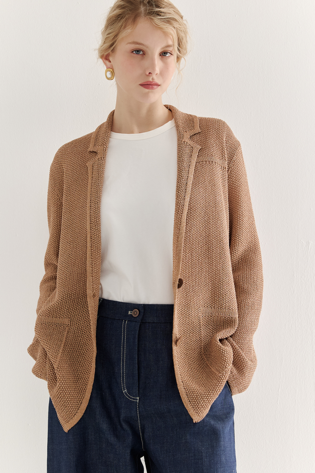 Жакет полуприлегающего силуэта  цвета бронзы из вязанного трикотажа, в составе которого вискоза и хлопок. Плотная скрутка нити образует упругое, но в то же время дышащее полотно. Цельно вязаные лацканы элегантно переходят в воротник, обрамляя вырез. Прямые рукава полной длины завершают лаконичный силуэт. Этот жакет станет изысканным дополнением к непринужденному городскому образу.
