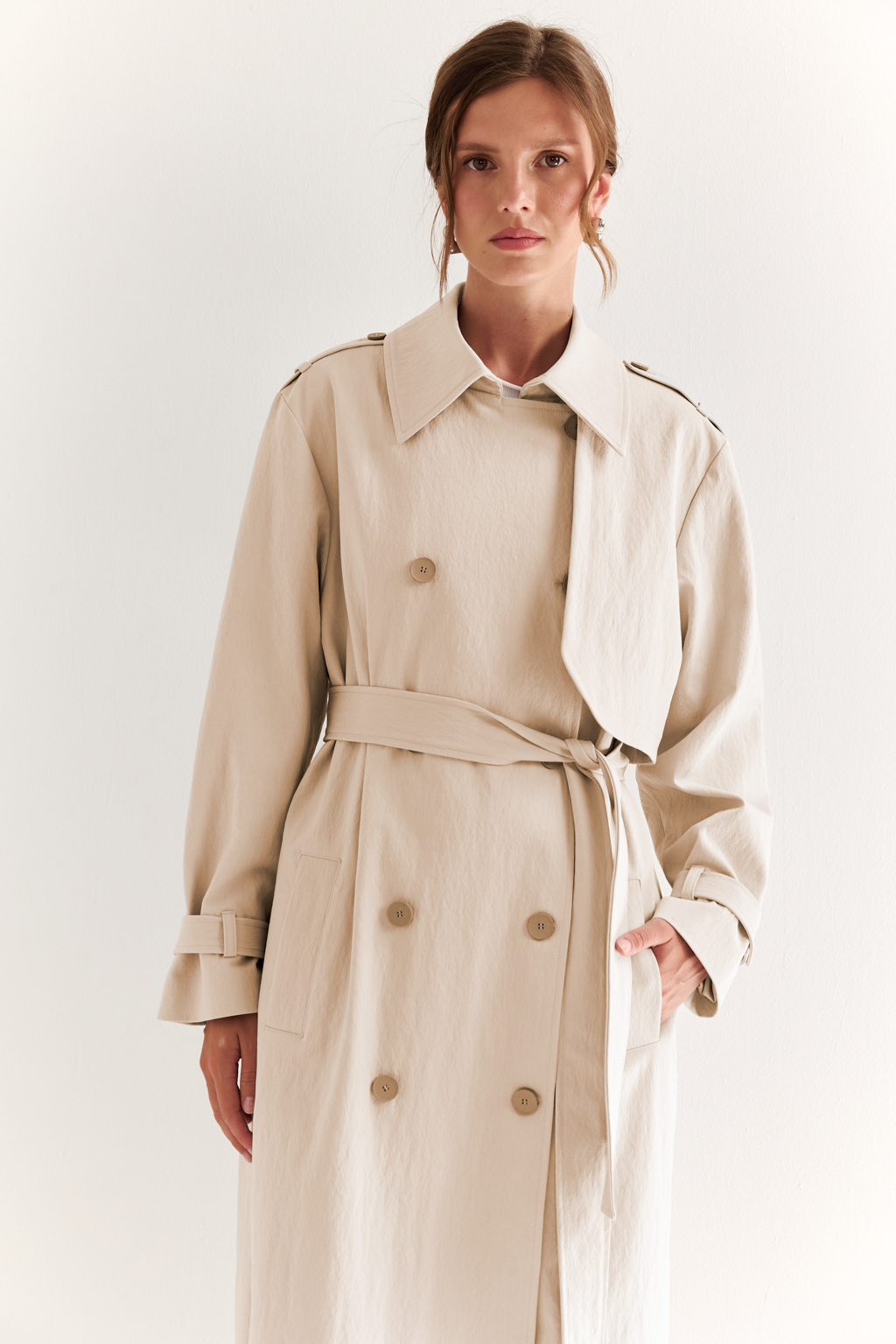 Плащ двубортный прямого силуэта длиной макси с расширенной линией плеча и отлётными кокетками по полочке и спинке. Приталивается завязывающимся поясом.