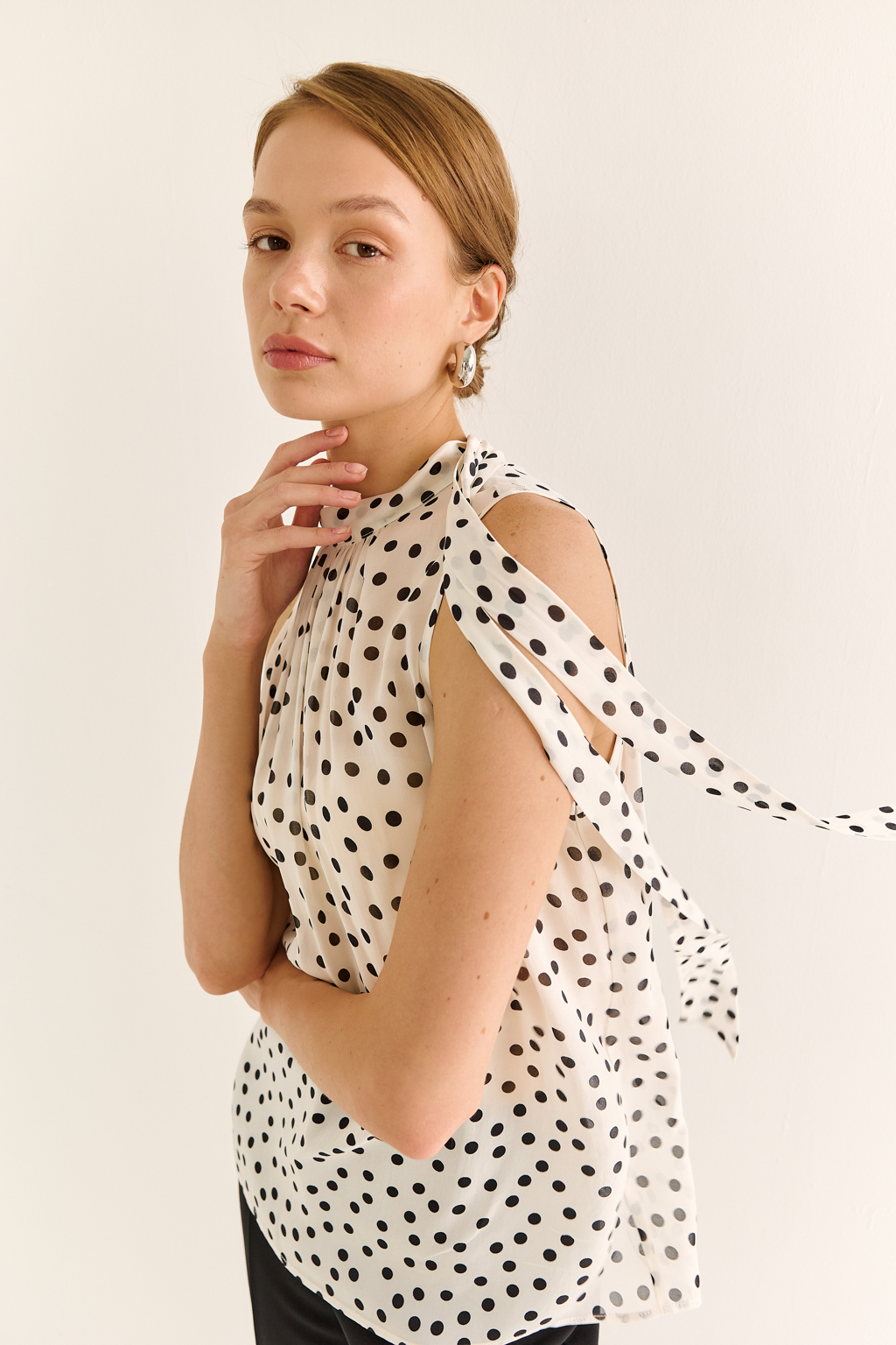 Блузка с бантом: женственность и утончённый акцент. Эта блузка без рукавов — воплощение элегантной простоты с выразительной деталью. Горловина украшена мягким бантом, который добавляет образу нотки утончённости и романтичного шика. Лёгкая драпировка спереди делает силуэт свободным, но изящным, подчёркивая вкус и стиль. Идеальна для офисных будней, деловых встреч или вечерних образов. Эффектно смотрится под жакет или кардиган, но и сама по себе становится акцентом. Сила — в деталях. Женственность — в каждом движении.