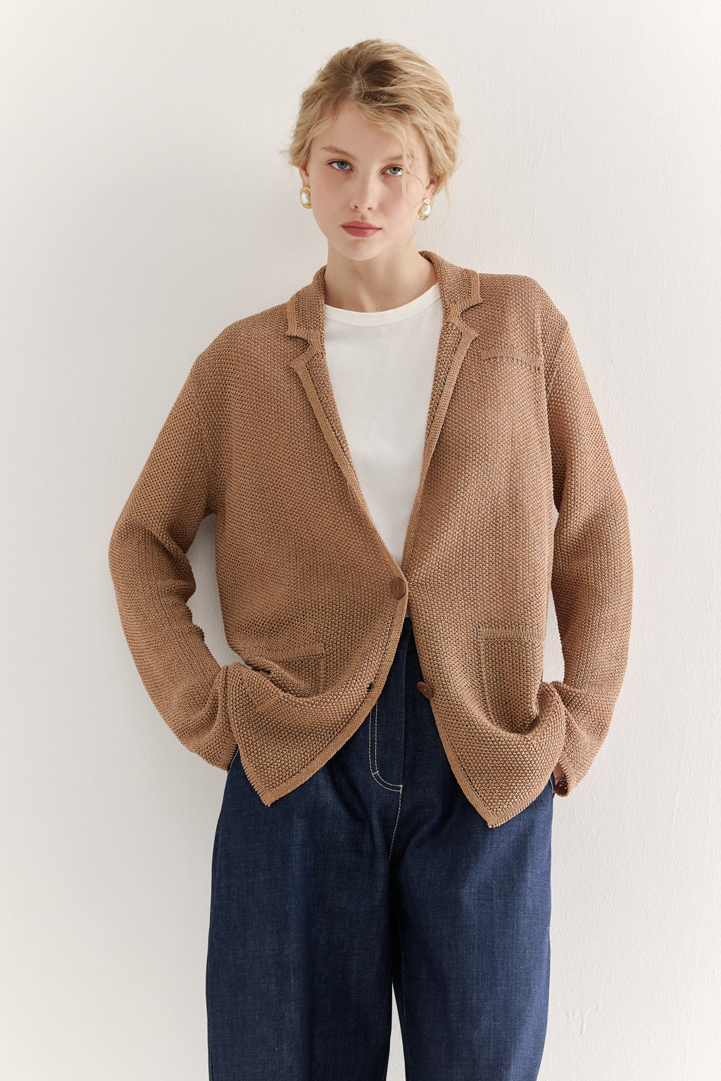 Жакет полуприлегающего силуэта  цвета бронзы из вязанного трикотажа, в составе которого вискоза и хлопок. Плотная скрутка нити образует упругое, но в то же время дышащее полотно. Цельно вязаные лацканы элегантно переходят в воротник, обрамляя вырез. Прямые рукава полной длины завершают лаконичный силуэт. Этот жакет станет изысканным дополнением к непринужденному городскому образу.