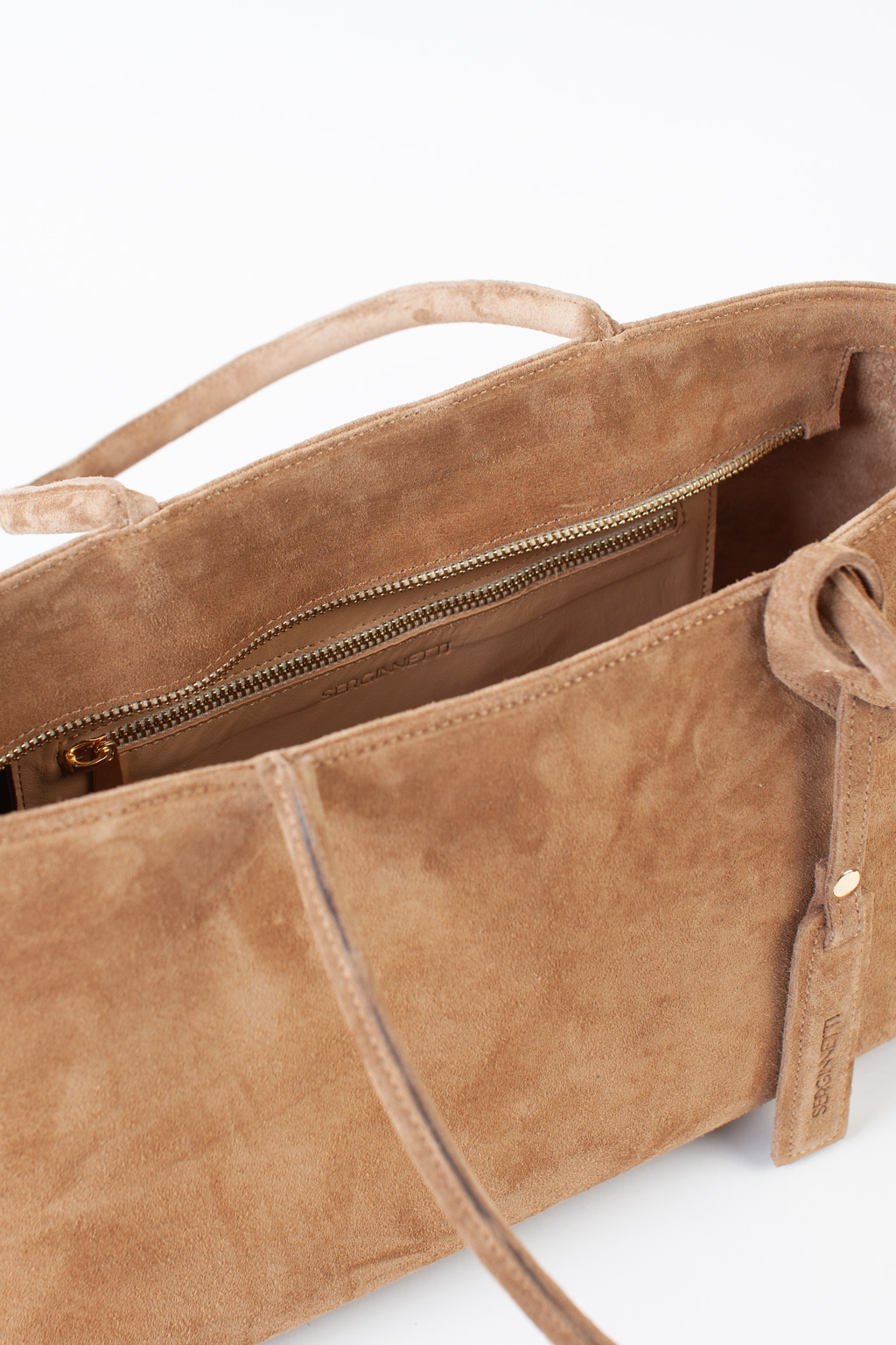 Сумка-тоут выполнена из натуральной замши. Аксессуар закрывается на металлическую молнию,имеет удобные ручки и брелок. Размеры сумки: 45*21*5,8 см.