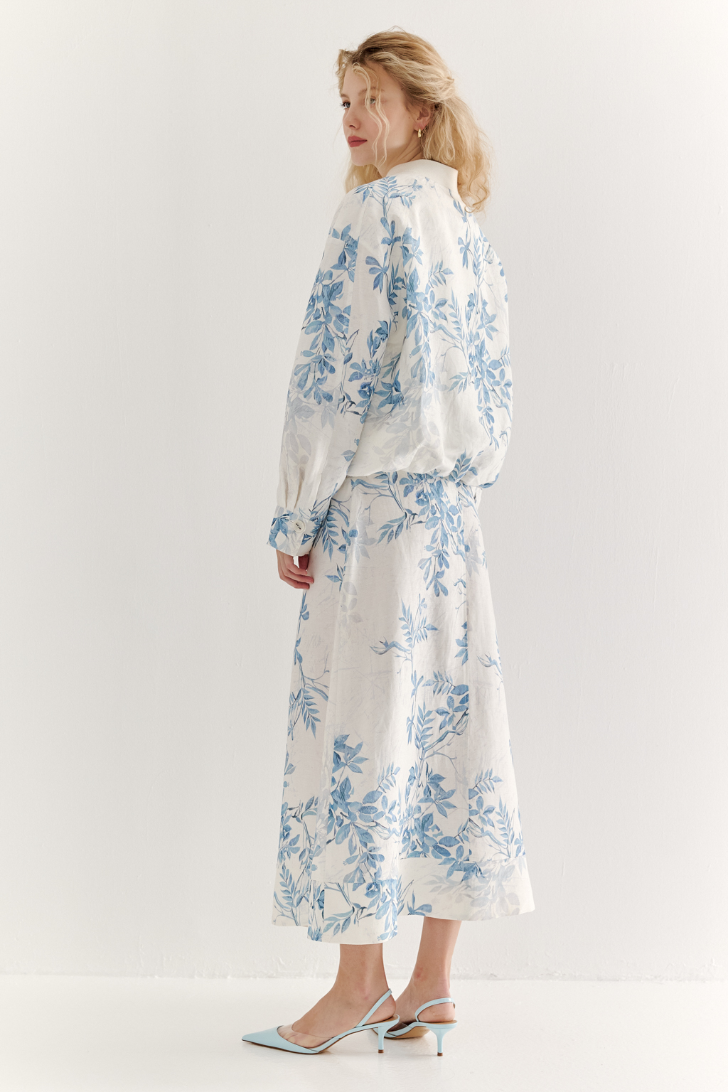 Юбка А-силуэта выполнена из ткани, в составе которой лен и вискоза. Классические детали, такие как пояс, шлевки, гульфик, кокетка спинки и отстроченные швы, представляют собой традиционное решение для джинсовых коллекций. Изюминкой модели является глубокая складка по переднему шву, обеспечивающая дополнительный комфорт и свободу движений. Главный акцент – принт в стиле знаменитого одноцветного Туаль де Жуи, где диагональная композиция из листьев и цветов выполнена в голубом цвете.