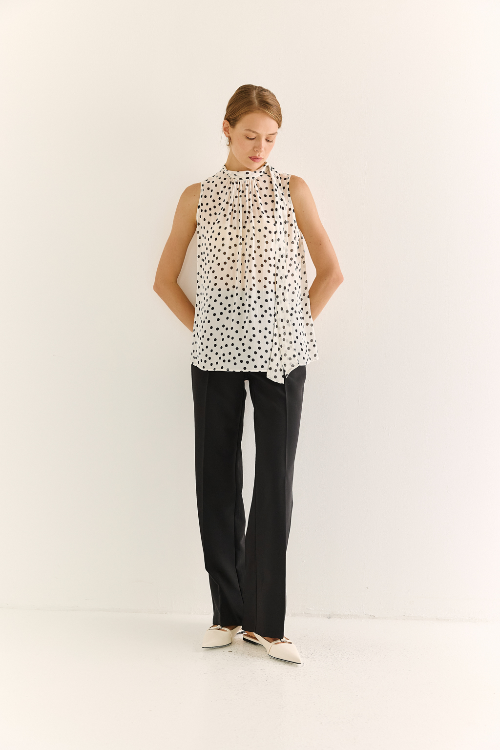 Блузка с бантом: женственность и утончённый акцент. Эта блузка без рукавов — воплощение элегантной простоты с выразительной деталью. Горловина украшена мягким бантом, который добавляет образу нотки утончённости и романтичного шика. Лёгкая драпировка спереди делает силуэт свободным, но изящным, подчёркивая вкус и стиль. Идеальна для офисных будней, деловых встреч или вечерних образов. Эффектно смотрится под жакет или кардиган, но и сама по себе становится акцентом. Сила — в деталях. Женственность — в каждом движении.