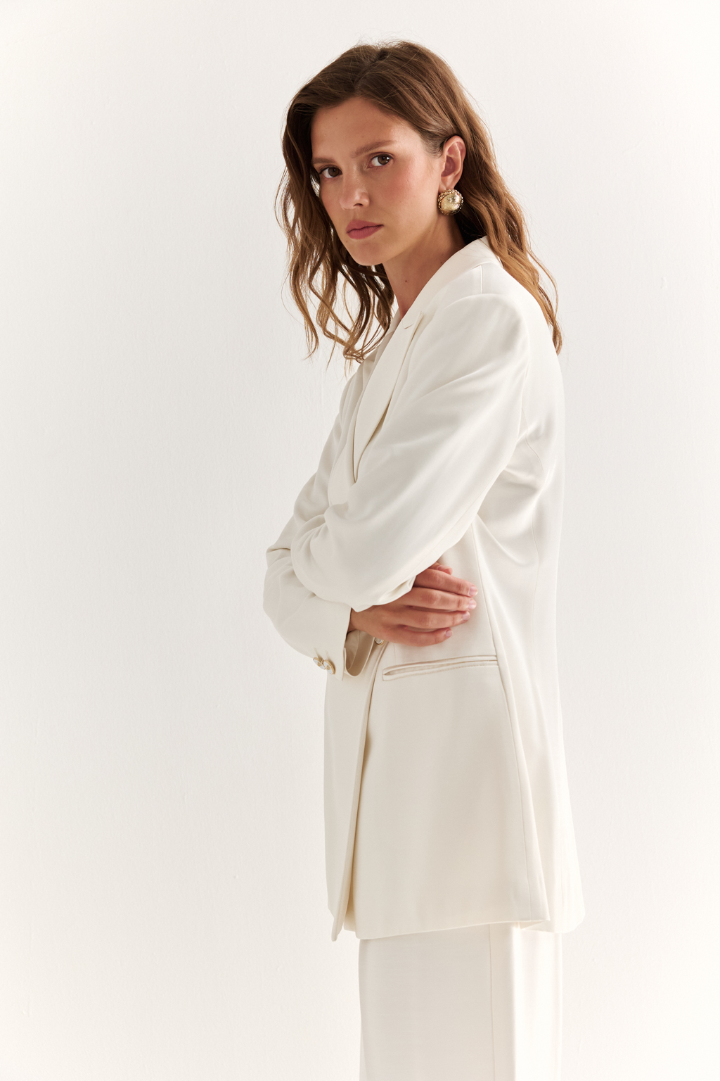 Двубортный жакет: классика в современной геометрии. Удлинённый двубортный жакет — это база, которая говорит о статусе без слов. Чёткие плечи, графичный крой и острые лацканы формируют уверенный, собранный образ. Рельефы по спинке и бокам подчёркивают силуэт, обеспечивая идеальную посадку, а карманы добавляют практичности и сдержанного акцента. Идеален в паре с классическими брюками, юбкой-карандашом или джинсами. Работает как в деловом комплекте, так и в вечерней стилизации. Современная структура с уважением к традиции.