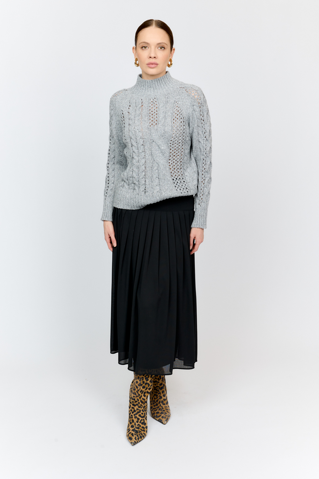 Свитер серого цвета из мягкой пряжи фигурной вязки с ассиметричными косами, с высокой горловиной и длинным рукавом реглан отлично стилизуется с денимом и обувью на плоском ходу.