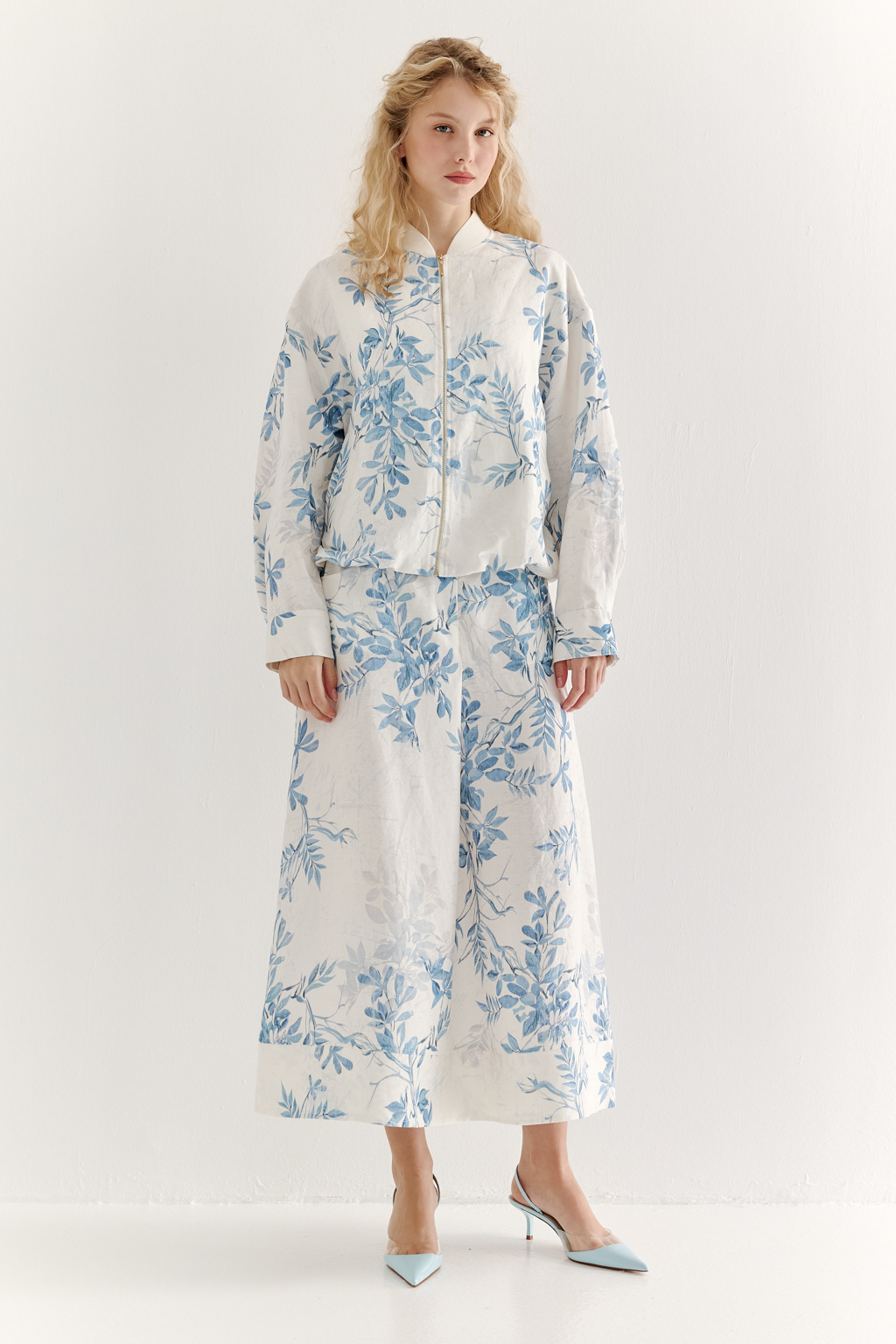 Юбка А-силуэта выполнена из ткани, в составе которой лен и вискоза. Классические детали, такие как пояс, шлевки, гульфик, кокетка спинки и отстроченные швы, представляют собой традиционное решение для джинсовых коллекций. Изюминкой модели является глубокая складка по переднему шву, обеспечивающая дополнительный комфорт и свободу движений. Главный акцент – принт в стиле знаменитого одноцветного Туаль де Жуи, где диагональная композиция из листьев и цветов выполнена в голубом цвете.