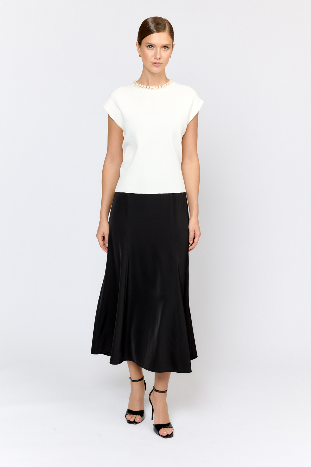 Элегантный топ  с круглой горловиной, декорированной тесьмой. Со спущенным плечом, без рукавов. Свободного силуэта. Изысканная модель из премиального  трикотажа плотной вязки в  молочном цвете. Сбалансированная комбинация вискозы и полиамида  создает комфорт при носке. Материал хорошо держит форму  и не подвержен деформации.  Лаконичный топ с декоративной тесьмой  в молочном оттенке - утонченное решение для вечерних или деловых образов.