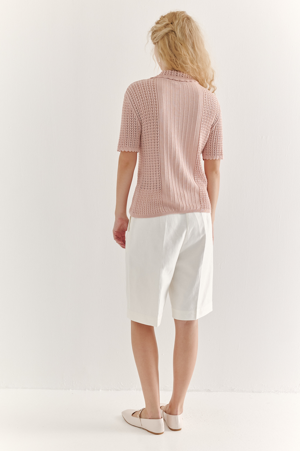 Джемпер-поло нежно-розового цвета полуприлегающего силуэта средней длины из вискозной пряжи, выполнен в комбинации полупрозрачной сетки и жаккарда, низ рукава и оторочка воротника - изящные фестоны. Рукав короткий, застежка на укороченной планке горловины на три пуговицы.