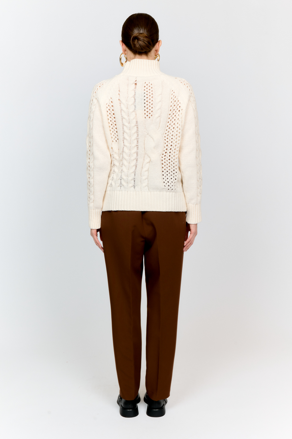 Свитер молочного цвета из мягкой пряжи фигурной вязки с ассиметричными косами, с высокой горловиной и длинным рукавом реглан отлично стилизуется с денимом и обувью на плоском ходу.