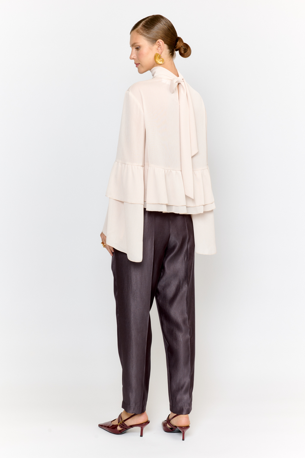 Блуза свободного кроя с легким расширением к низу с воланами и воротником-стойкой, переходящим в ленты, которые можно завязать в бант либо просто перекинуть через плечи. Выполнена из легкой полупрозрачной ткани. Крэш-шифон -легкий, дышащий материал, создающий эффект невесомости. Полиэстеровые волокна в составе обеспечивают   неприхотливость в уходе и устойчивость к механическим повреждениям. Нежный цвет экрю позволяет легко вписать блузу в гардероб, для создания как праздничных образов, так и повседневных.