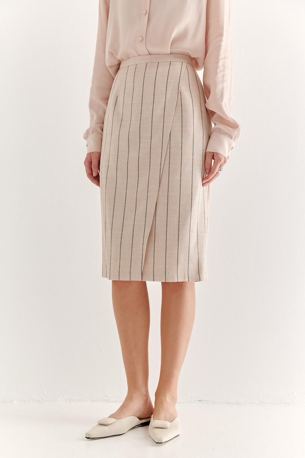 Прямая юбка с запахом выполнена из ткани, представляющей собой уникальную разработку бренда. Сочетание волокон хлопка, вискозы, полиэстера и эластана обеспечивает максимальный комфорт и практичность изделия. Нежный пудрово-розовый оттенок эффектно подчёркнут модной шоколадно-коричневой полоской в широком раппорте. Юбка идеально сочетается с жакетом архитектурного кроя из той же ткани, создавая завершённый формальный образ.