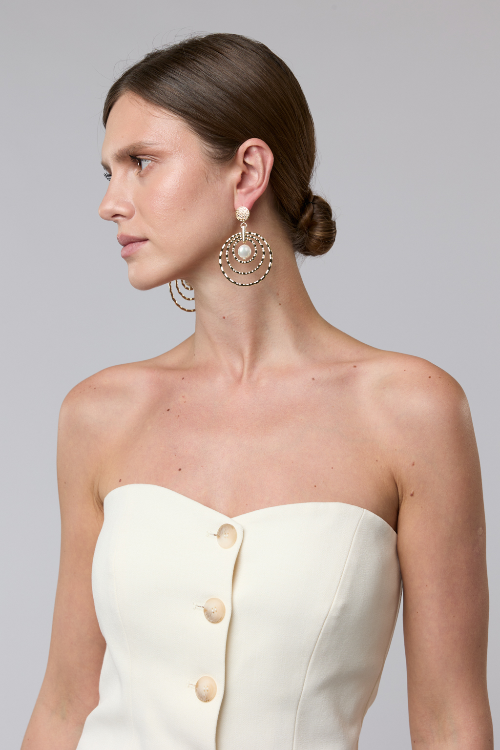 Современные крупные дизайнерские серьги из коллекции "Classic line" выполнены из металла золотого цвета в виде уменьшающихся  колец и центральной подвески из майорки. Свободная закрепка и рифленая фактура создают эффект мерцания при движении. Вес 10 г, длина - 7 см. Украшение выполнено из гипоаллергенного сплава со стойким гальваническим покрытием.