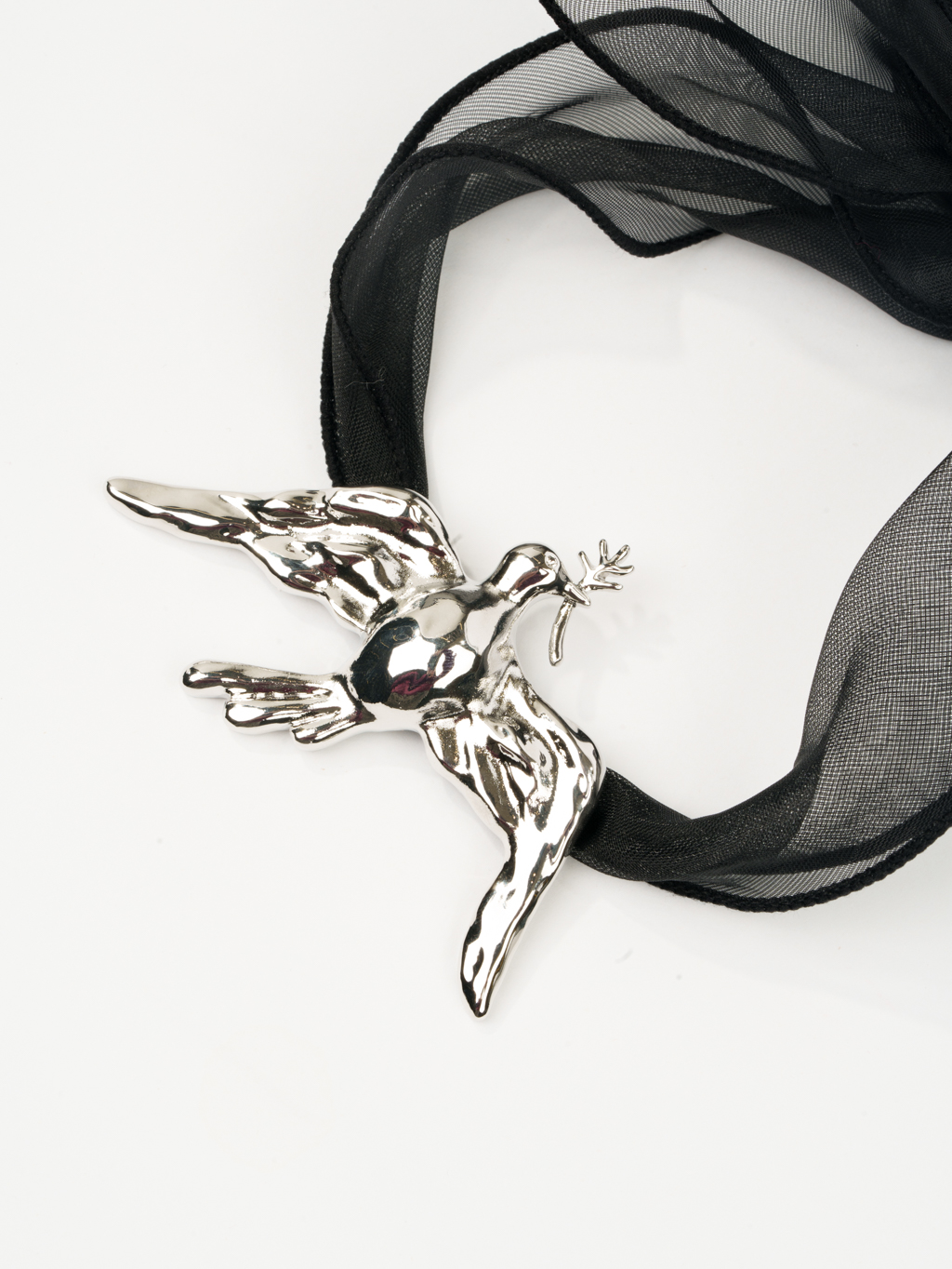 Дизайнерское колье с металлическим кулоном в виде летящей птицы серебряного цвета на текстильной ленте из черной плотной органзы. Длина ленты позволяет варьировать стиль колье. Украшение выполнено из гипоаллергенного сплава с гальваническим покрытием.  Вес колье составляет 39 гр, длина до 140 см.