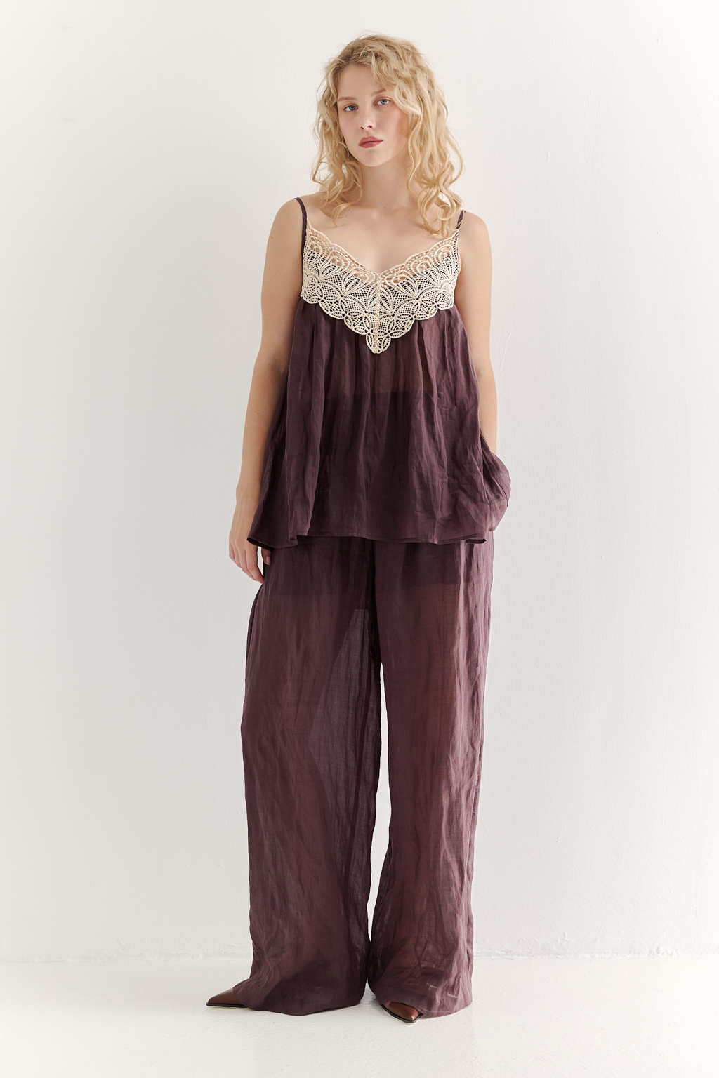 Топ-трапеция, выполненный из стопроцентной крапивы с крэш-эффектом благородного коричневого оттенка, украшен отделкой из кружевного гипюра нежного бежевого цвета. Кружевная деталь изысканно располагается на передней части изделия. Деталь переда топа настрочены на кружево со сборкой, по верхнему срезу спинки предусмотрена резинка, обеспечивающая оптимальную посадку. Бретели топа регулируются. Топ представляет собой идеальный комплект с брюками из крапивы, льна или хлопка, создавая гармоничный и стильный образ