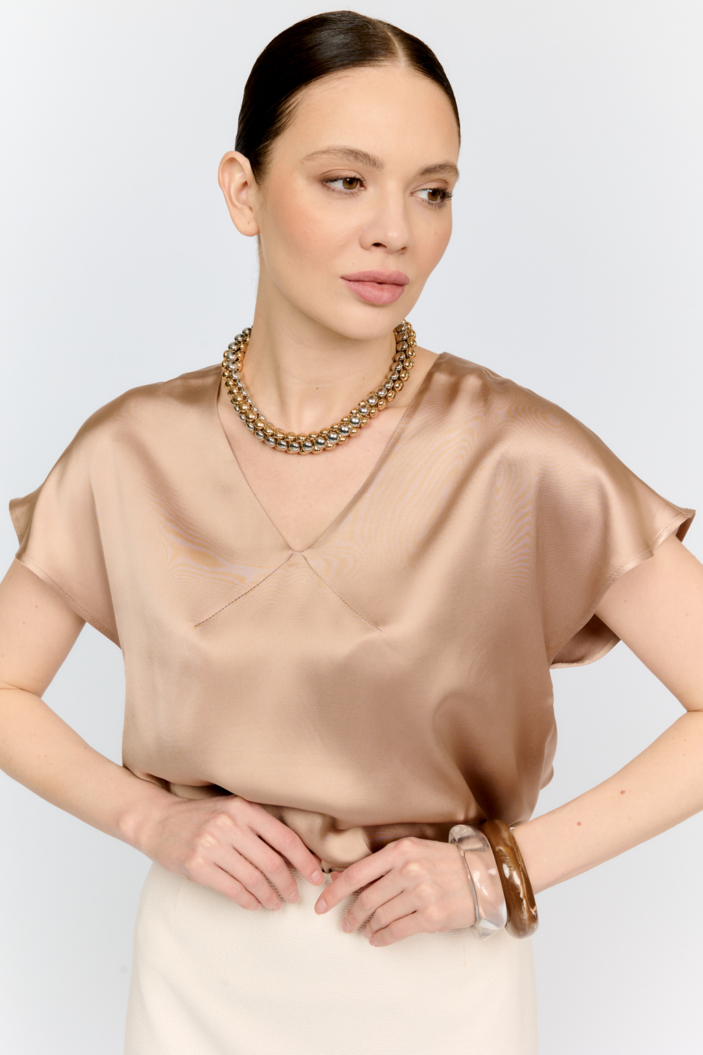 Топ с v-образным вырезом горловины из струящейся и переливающейся вискозы песочного цвета со спущенной линией плеча - отличная база для множества комплектов.