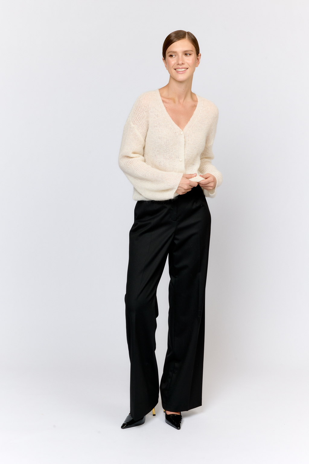 Кардиган с центральной застежкой на пуговицы, V-образной горловиной и длинным рукавом.  Модель свободного силуэта в уютном молочном оттенке из воздушной пряжи с шерстью и мохером с деликатными мелкими пайетками, придающими легкое сияние. Кардиган очень теплый, несмотря на свою трендовую транспарентность и легкость, благодаря мохеру в составе. Шерсть так же обеспечивает естественную терморегуляцию и уют. Такой кардиган будет выигрышно смотреться в образах с  брюками и юбками из коллекции, а так же дополнит образы с платьями на бретелях или платьем-бандо.