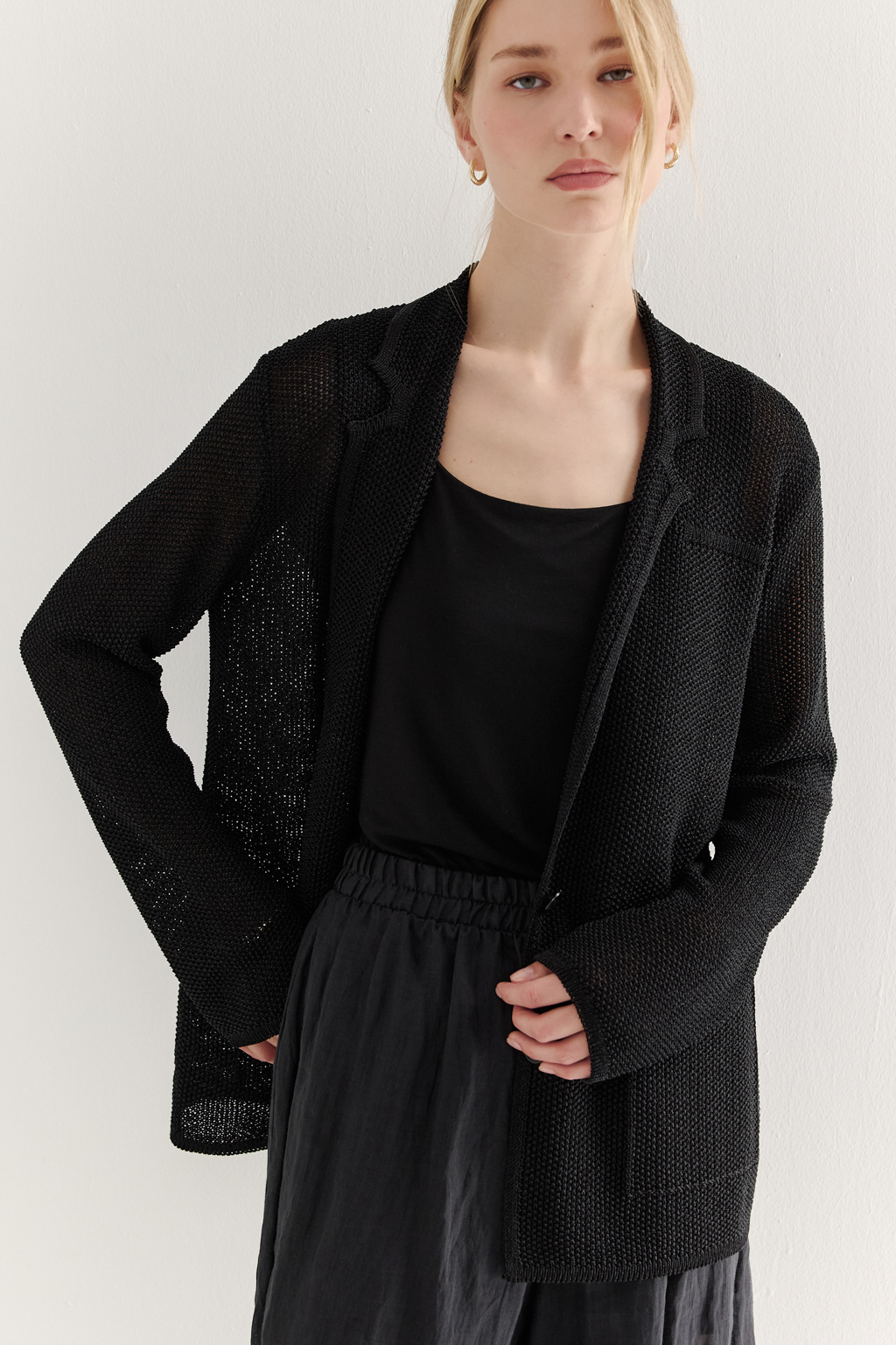 Жакет полуприлегающего силуэта черного цвета из вязаного трикотажа, в составе которого вискоза и хлопок. Плотная скрутка нити образует упругое, но в то же время дышащее полотно. Цельно вязаные лацканы элегантно переходят в воротник, обрамляя вырез. Прямые рукава полной длины завершают лаконичный силуэт. Этот жакет станет изысканным дополнением к непринужденному городскому образу.
