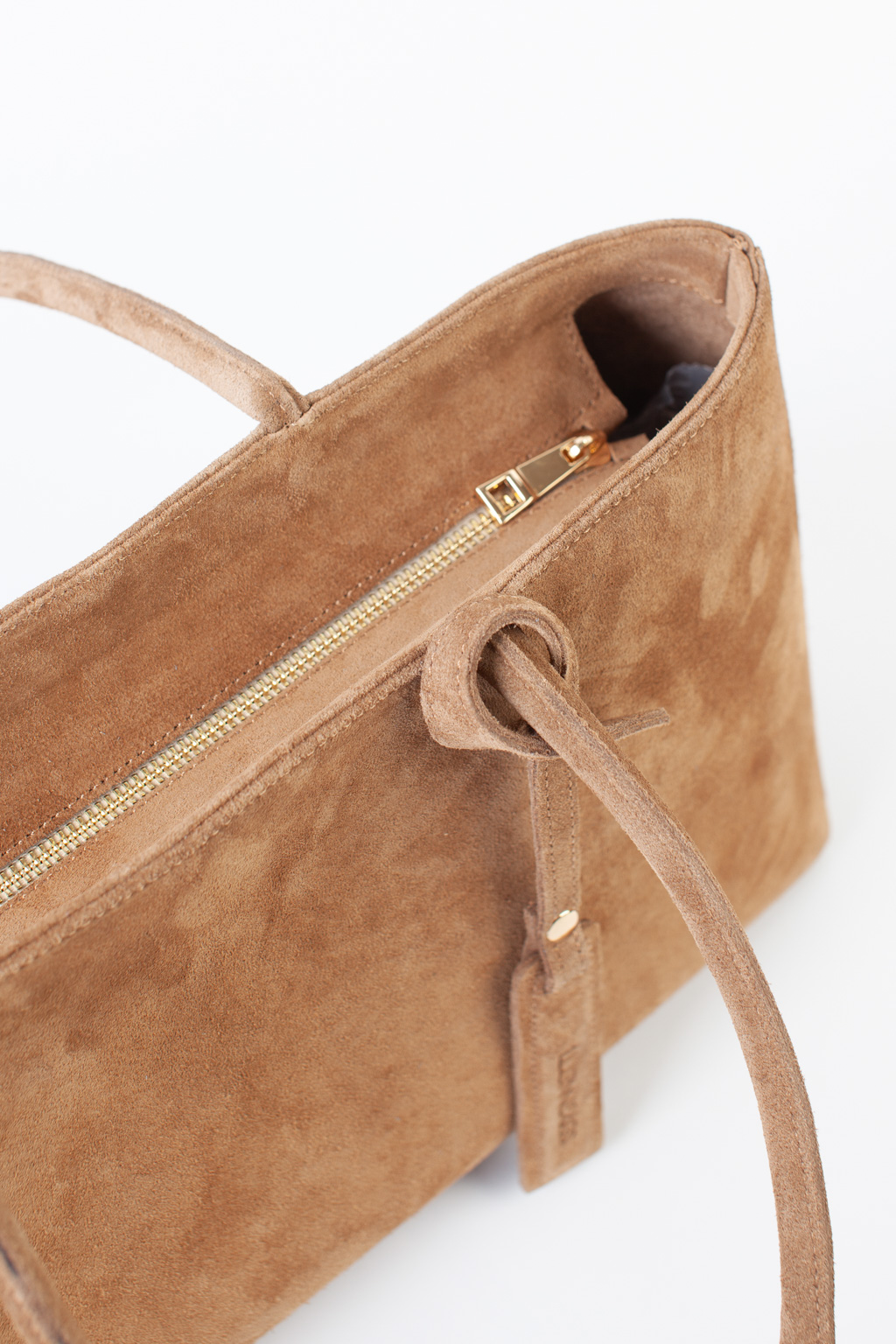 Сумка-тоут выполнена из натуральной замши. Аксессуар закрывается на металлическую молнию,имеет удобные ручки и брелок. Размеры сумки: 45*21*5,8 см.