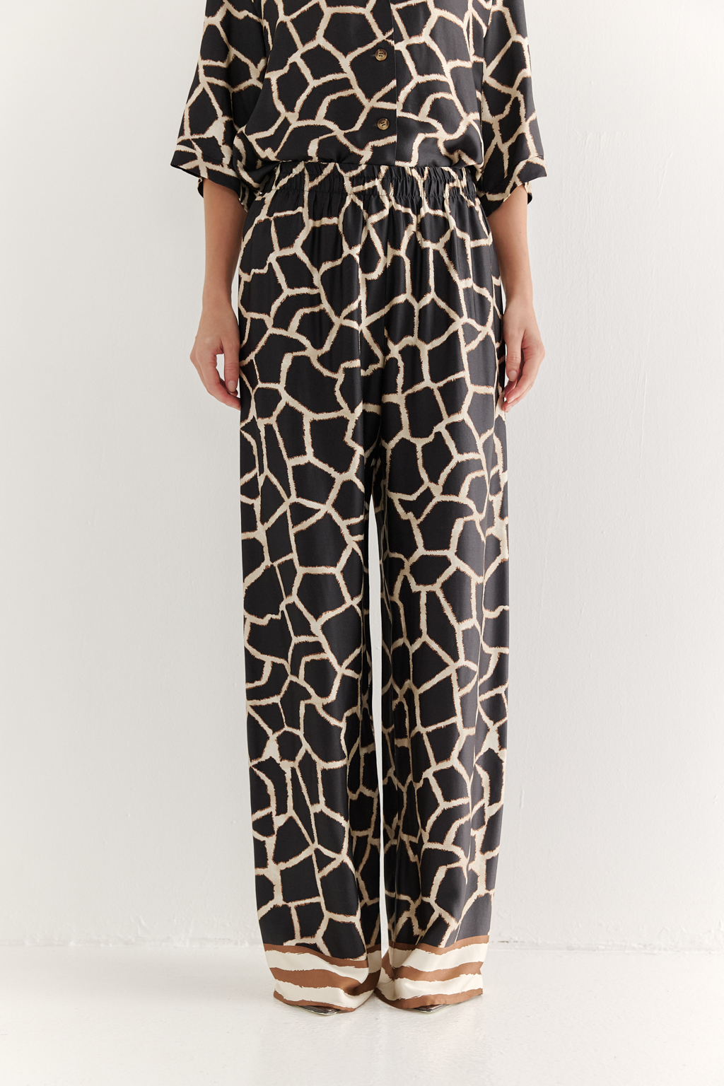Брюки, широкие и прямые по всей длине, выполнены из полированной вискозы с шелковистой текстурой, украшена эксклюзивным анималистическим принтом, разработанным дизайнерами бренда. Основной тренд - создание атмосферы комфорта, пронизанной заботой и бережным отношением к себе. Брюки оснащены удобными карманами и эластичным поясом, обеспечивающими максимальный комфорт и удобство. По низу брюк – контрастный по цвету бордюр. Идеальным дополнением к этим брюкам станут блуза из той же коллекции, а так же объёмный трикотажный кардиган.