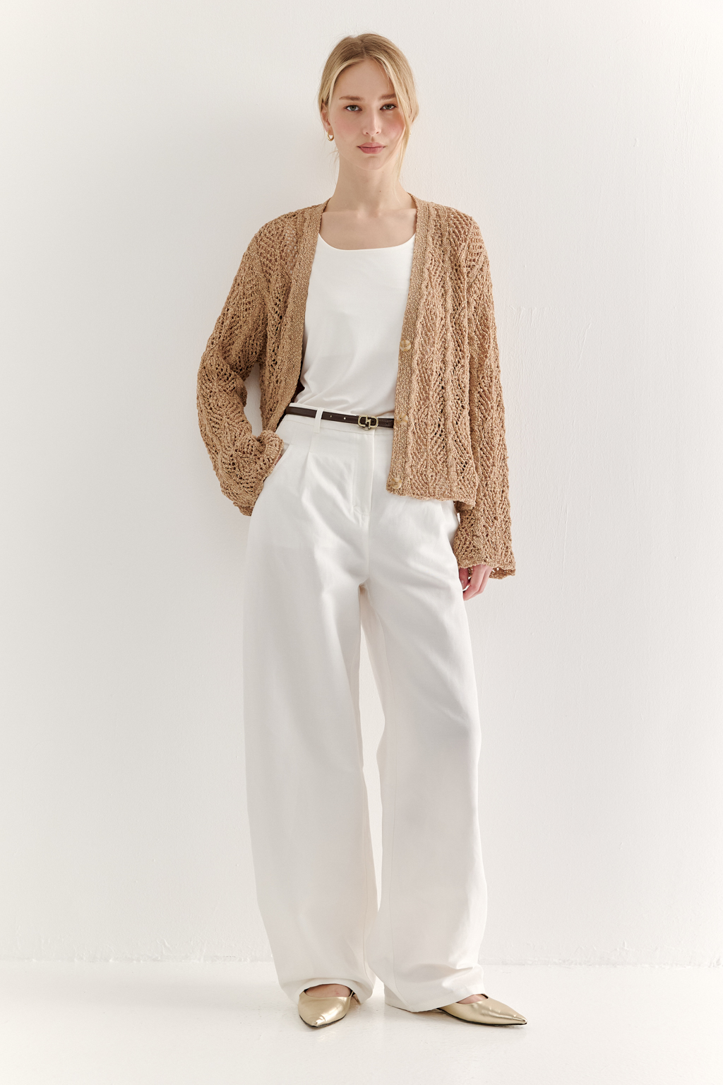 Бежевый вязаный кардиган оверсайз силуэта из хлопковой пряжи. Кардиган связан в сложной технике комбинирования сетки и ажурных ромбов. Рукав прямой удлиненный, V-образный вырез, борт отделан планкой, застежка по борту на 3 пуговицы, низ кардигана и рукав – сложные фестоны.