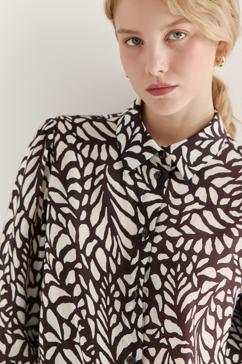 Блуза из легкой блузочной ткани с эффектом шелка со стилизованным растительным принтом в шоколадно-молочной гамме. Комфортная блуза имеет рубашечный воротник со стойкой, длинный рукав с манжетами, застёгивается на пуговицы.