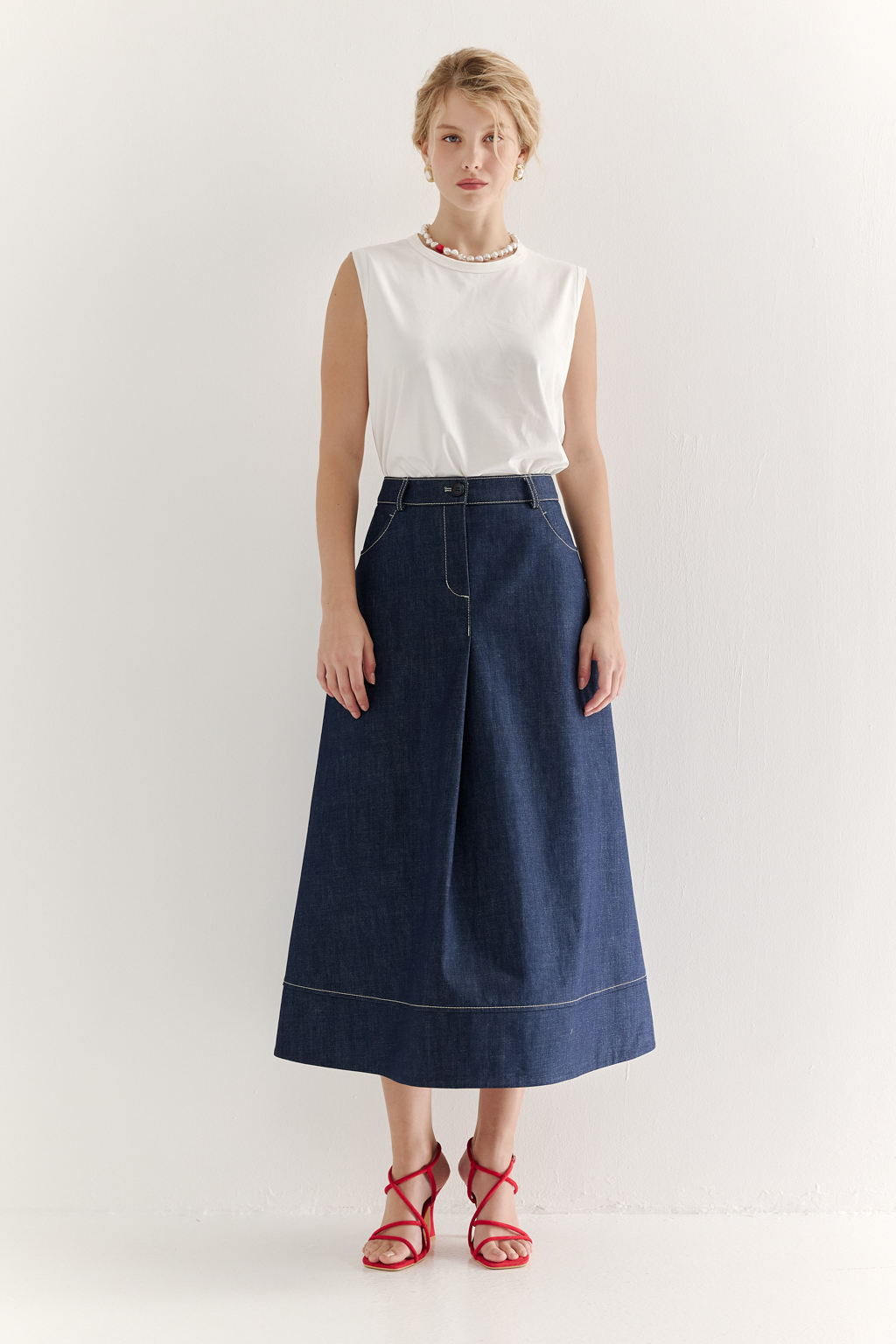 Топ-майка из хлопкового трикотажа молочного цвета в монохромном решении, горловина и проймы обработаны основным материалом.