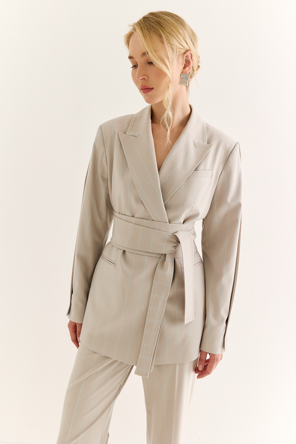 Жакет с поясом-кушаком: мягкая сила и подчёркнутая линия. Этот жакет сочетает в себе структурированную форму и пластичность драпировки. Приталенный силуэт акцентирован широким поясом-кушаком, который завязывается на талии, формируя выразительную линию «песочных часов» и добавляя образу женственности без излишней строгости.
Острые лацканы, аккуратная линия плеч и выверенный крой рукавов делают модель универсальной: для делового дня, кэжуал-комплекта или вечернего выхода. Пояс, завязанный на узел или бант, задаёт настроение и подчеркивает индивидуальность. Гармония формы и мягкости. Жакет, который раскрывает силу через утончённость.
