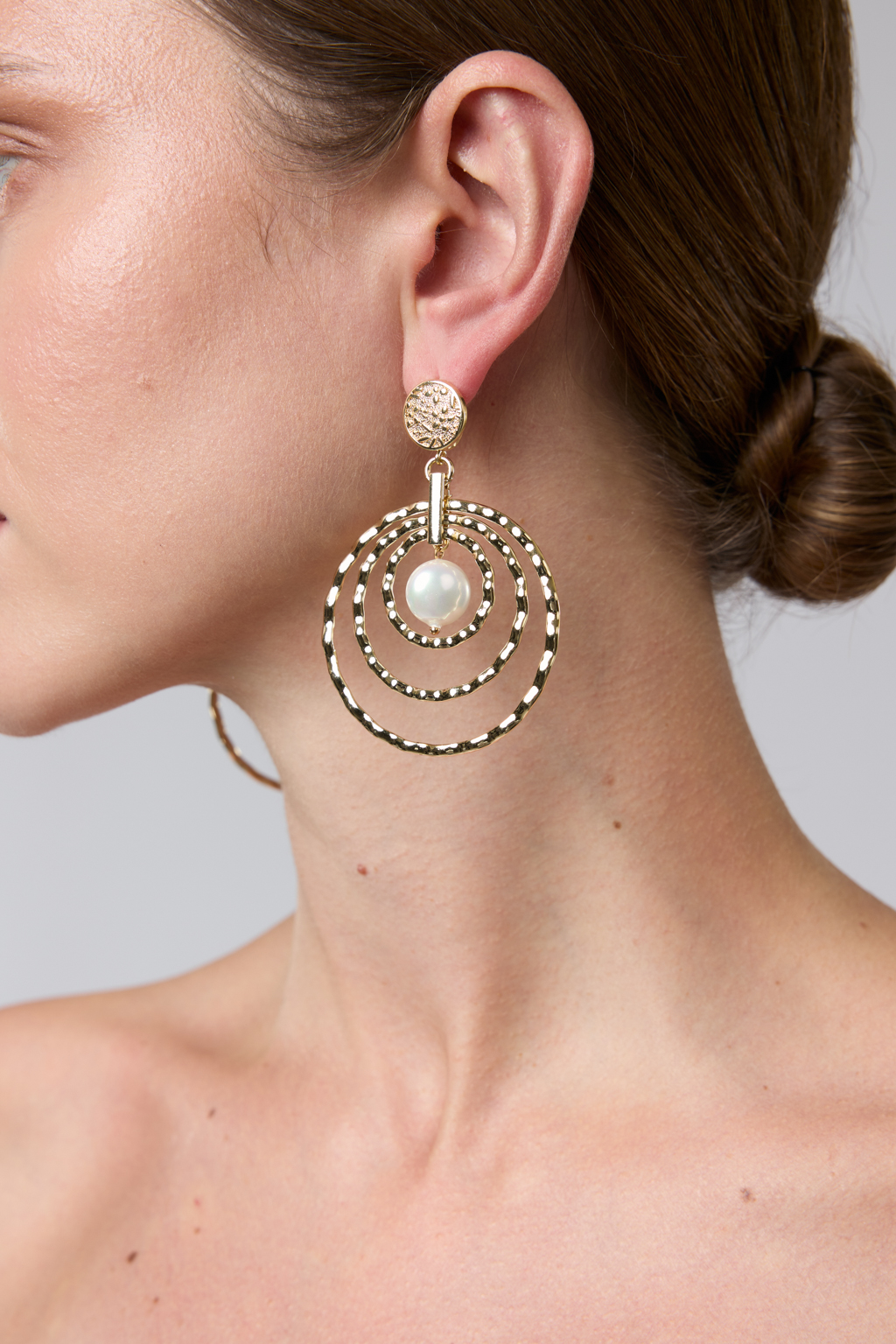 Современные крупные дизайнерские серьги из коллекции "Classic line" выполнены из металла золотого цвета в виде уменьшающихся  колец и центральной подвески из майорки. Свободная закрепка и рифленая фактура создают эффект мерцания при движении. Вес 10 г, длина - 7 см. Украшение выполнено из гипоаллергенного сплава со стойким гальваническим покрытием.