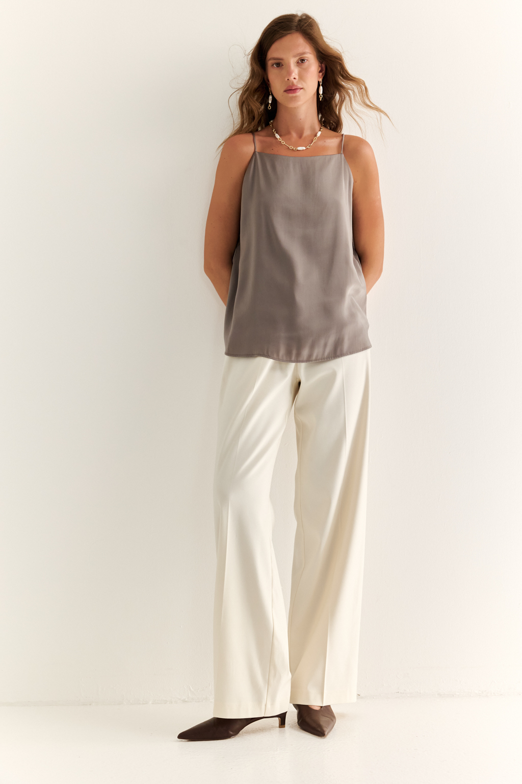 Прямые брюки: свобода, стиль, структура. Эти брюки с высокой посадкой и ровным силуэтом — воплощение современной женственности. Чёткие стрелки вытягивают силуэт, подчёркивая стройность ног, а широкие штанины добавляют образу лёгкости и статуса. Минималистичный дизайн с застёжкой на молнию и пуговицу, а также элегантный пояс делают модель идеальной для сочетания с жакетами, блузами или трикотажем. Идеальны как для офиса, так и для расслабленного городского образа. Современная классика, в которой сочетаются уверенность и комфорт.