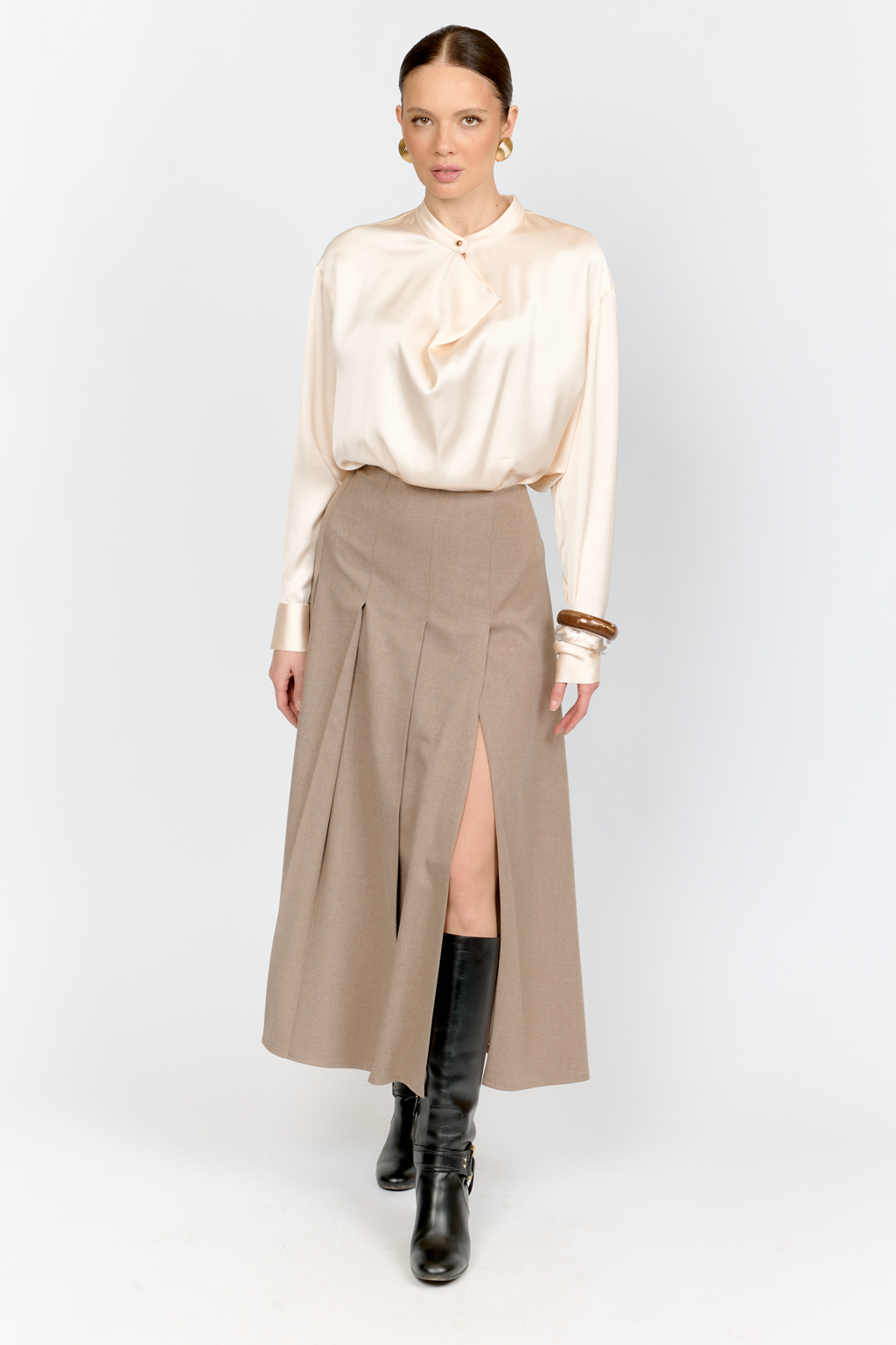 Блуза свободного кроя из шелковистой вискозы с интересной деталью в виде складки на горловине с застежкой на декоративную золотую пуговицу. Изделие придаст стильный акцент к любому образу.