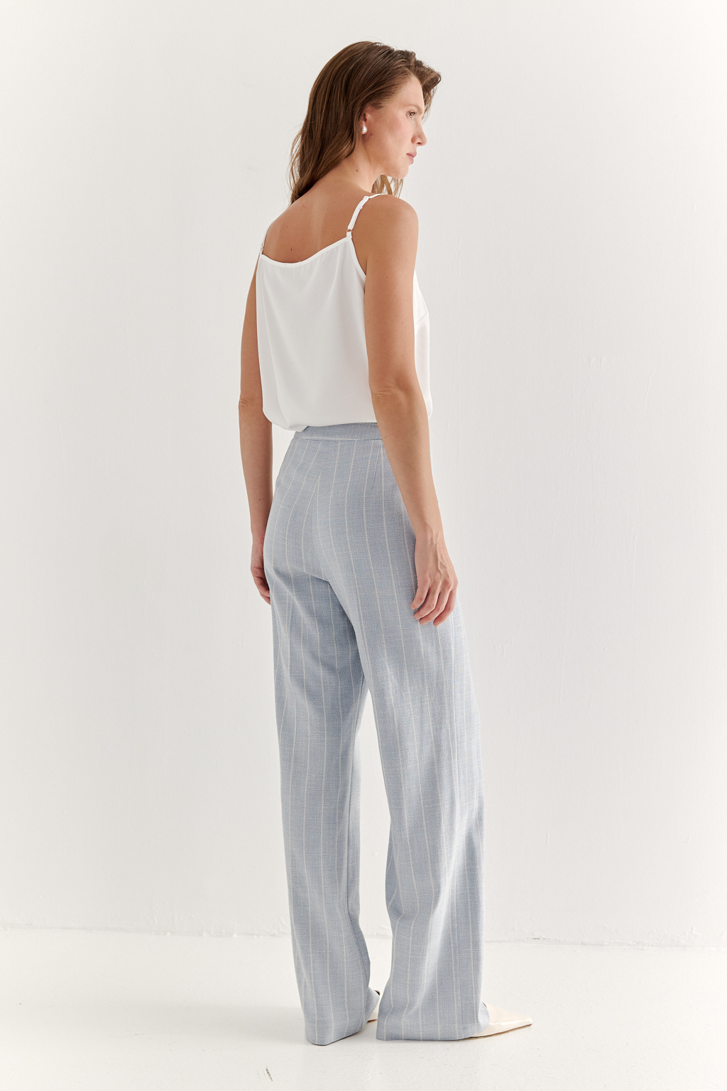 Эти брюки прямого силуэта созданы для абсолютного комфорта и расслабленной элегантности. Выполненные из ткани премиум-класса, они дарят невероятное ощущение мягкости, а нежный небесно-голубой оттенок эффектно подчеркнут светлой полоской в широком раппорте. Средняя посадка и удобные карманы делают их идеальными для любого типа фигуры. Ткань с оригинальным дизайном – эксклюзивная разработка бренда. Состав: хлопок, вискоза, эластан; за долговечность отвечает полиэстер. Брюки идеально дополнят городской look с жакетом архитектурного кроя их этой же ткани, создавая модный многослойный образ.