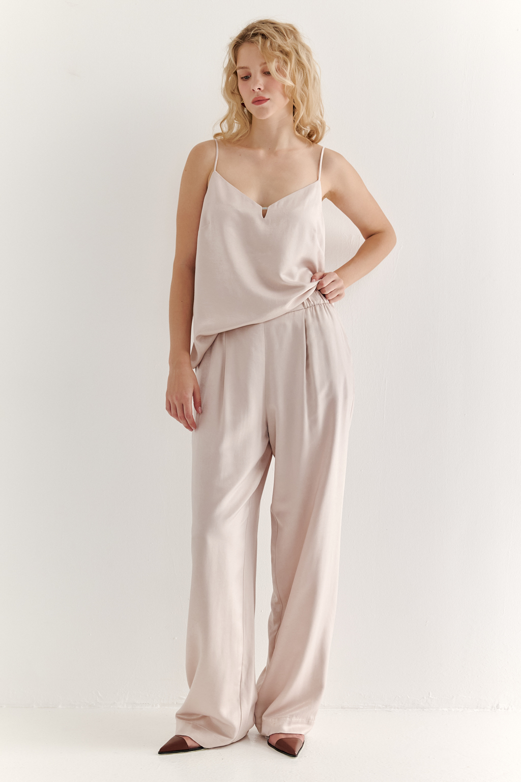 Топ из струящегося атласа с крэш эффектом в пудровом цвете. Топ на регулируемых бретелях свободного кроя с декором на линии декольте.